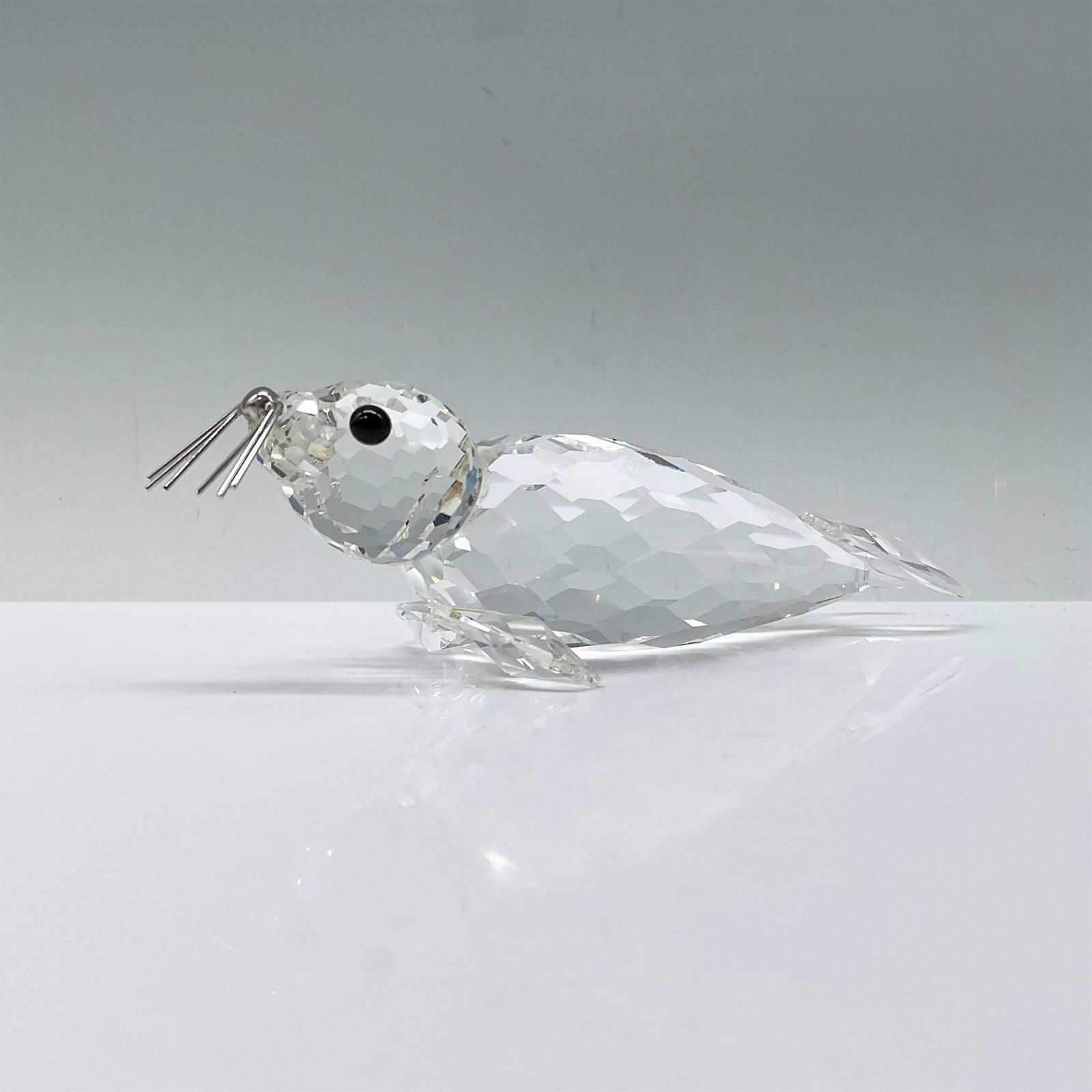 Swarovski Crystal Figurine, Seal 012621: A clear seal featuring spread-out flippers, black crystal eyes, and rhodium whiskers. Swarovski backstamp. Includes a Swarovski box. Dimensions of box: 4"H x 5" dia. Artist: Max Schreck Issued: 1985-1