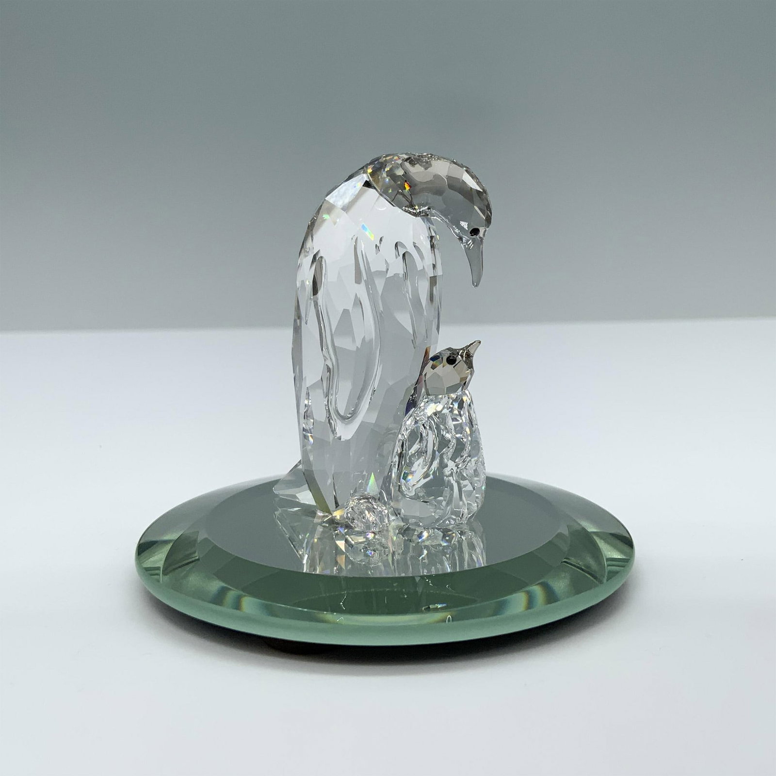 Swarovski Crystal Figurine, Penguin Mother and Baby: Beautiful wildlife scene featuring an Emperor penguin and its chick. Swarovski swan mark. This item has its original box. Box measures: 4.75"H x 3.25" dia. This item has a base included. 5043728. Arti