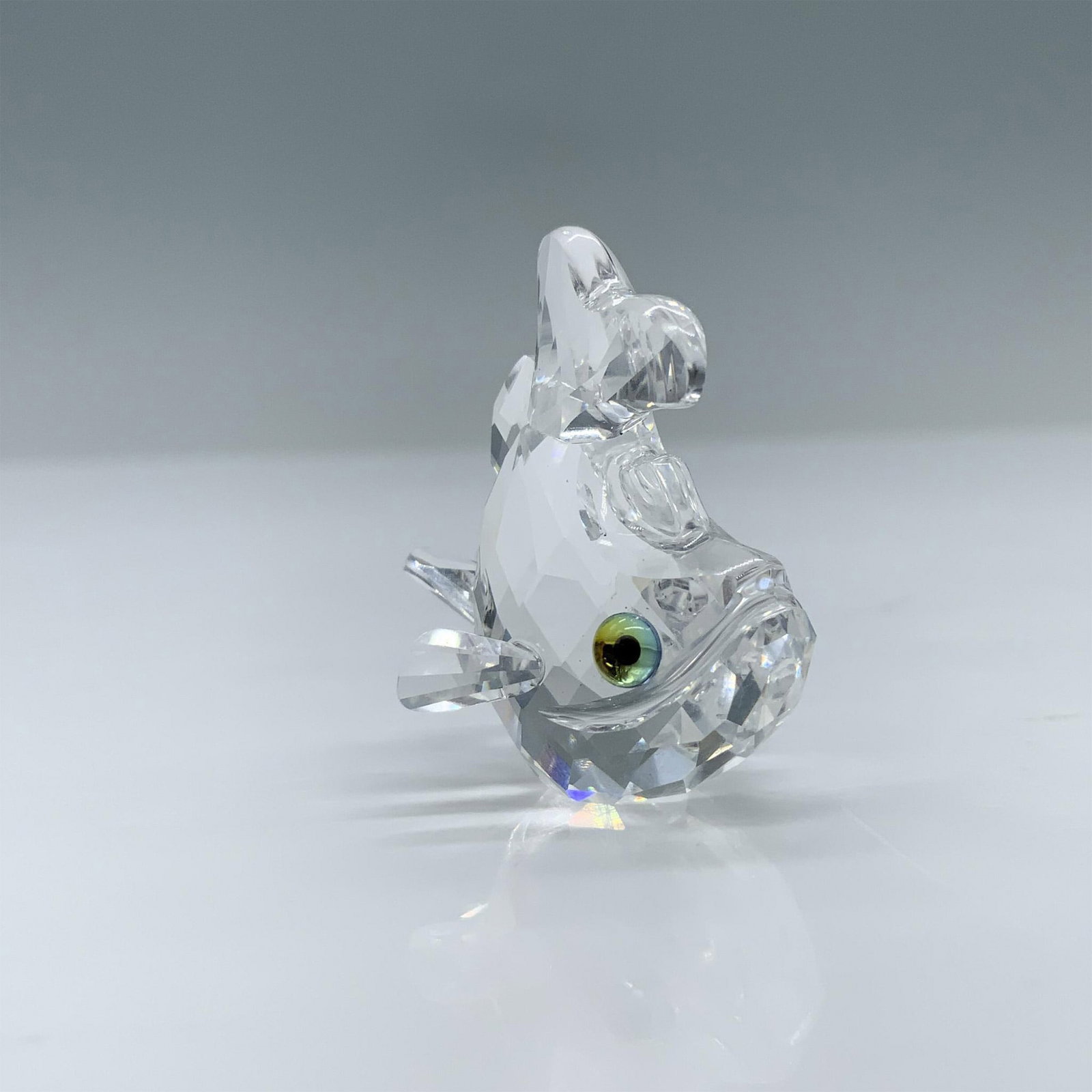 Swarovski Crystal Figurine, Baby Carp: Part of the Beauties of the Lake category. Features a clear crystal body with green eyes. Swarovski swan mark. Includes the original box, dimensions: 2.5"H x 3.25" dia. Artist: Michael Stamey Issued: 