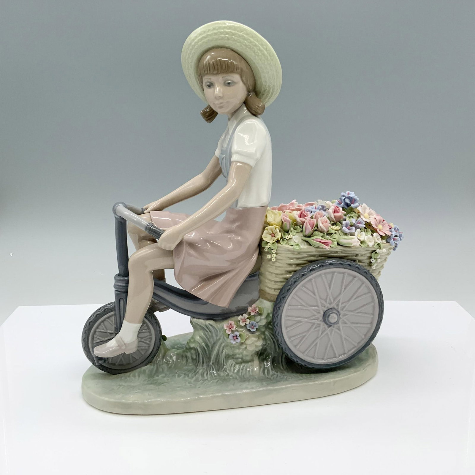 Girl With Flowers In Tow 1005031 - Lladro Porcelain Figurine: Glossy finish; Lladro backstamp. Artist: Francisco Catala Issued: 1979-1985 Dimensions: 9.75"L x 4.25"W x 10.25"H Manufacturer: Lladro Country of Origin: Spain