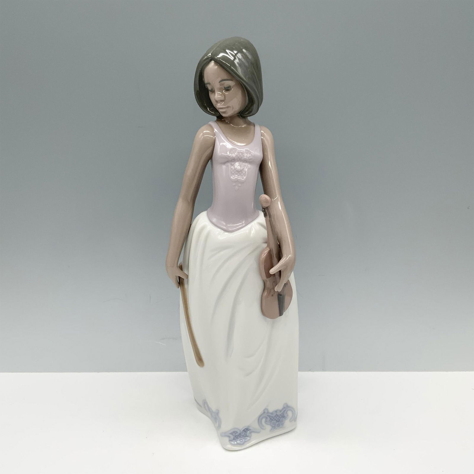 Nao by Lladro Porcelain Figurine, Sweet Melody 1338: Magnificent figure of a woman modeling a short bob hairstyle as she holds a violin and bow. Nao backstamp. This item has its original box 7.25"L x 5.75"W x 12.25"H. Issued: 1989 Dimensions: 3.75"L x 3