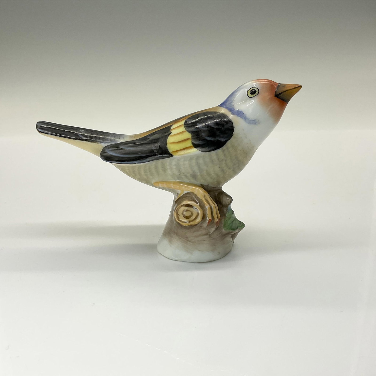 Herend Porcelain Figurine, Bird on Branch: A porcelain figurine of a bird perched on a branch intricately hand-painted in a realistic pattern. Herend backstamp. Issued: 1946 Dimensions: 4.5"L x 2"W x 2.75"H Manufacturer: Herend Country of Orig
