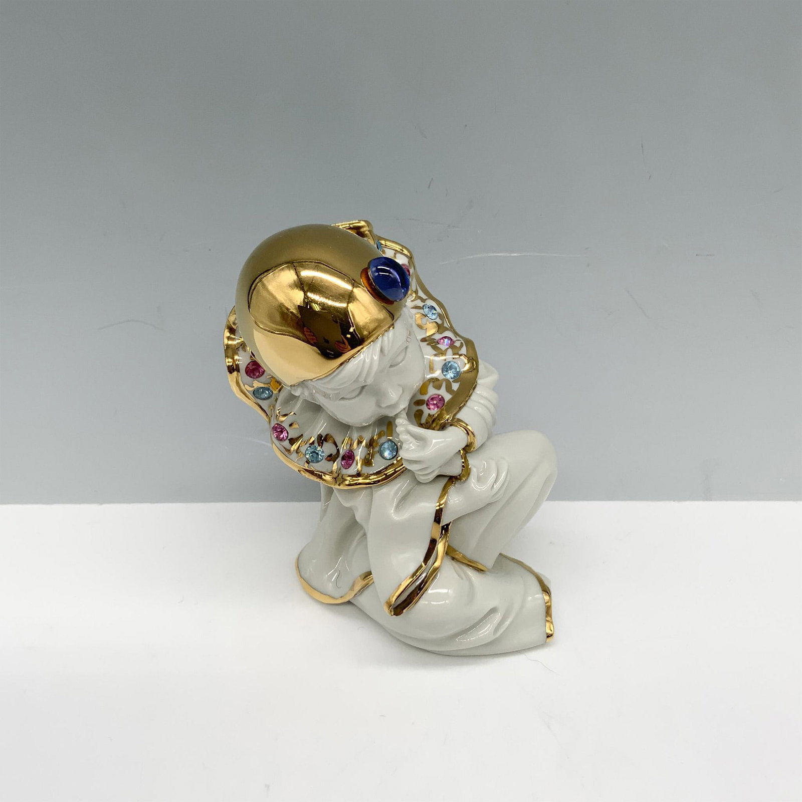 RG Oggetti and Capodimonte Porcelain Figurine, Harlequin Boy: Magnificent figurine of a boy sucking on his toe as he wears an outfit with glided accents and decorated with Swarovski crystals. Capodimonte backstamp and RG Italy impressed mark. Issued: 20th centur