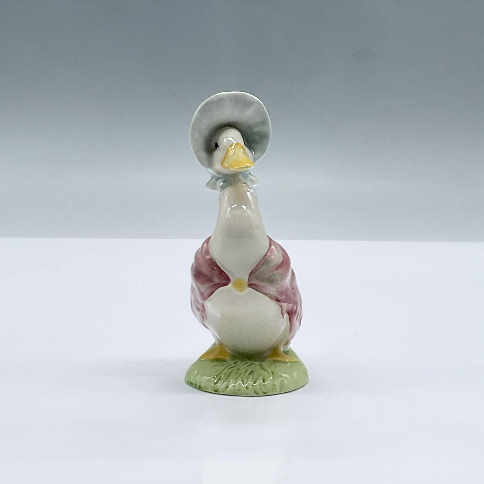 Royal Albert Beatrix Potter Figurine, Jemima Puddleduck: Glossy porcelain. Features a white duck wearing a blue headpiece and pink shawl. Royal Albert Beatrix Potter backstamp. This item has its original box, dimensions: 2.5"L x 2"W x 5"H. Issued: c. 1989 D
