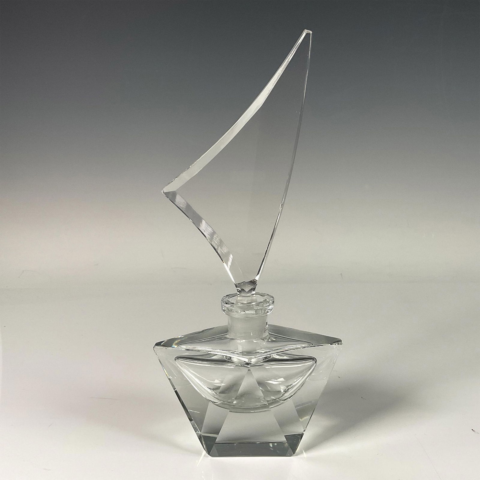 Crystal Perfume Bottle with Sail Shaped Stopper: Stunning perfume bottle featuring a unique stopper in the form of windswept sails, resting elegantly on geometric, faceted diamond shaped base. Dimensions: 4.25"L x 2.5"W x 8.75"H