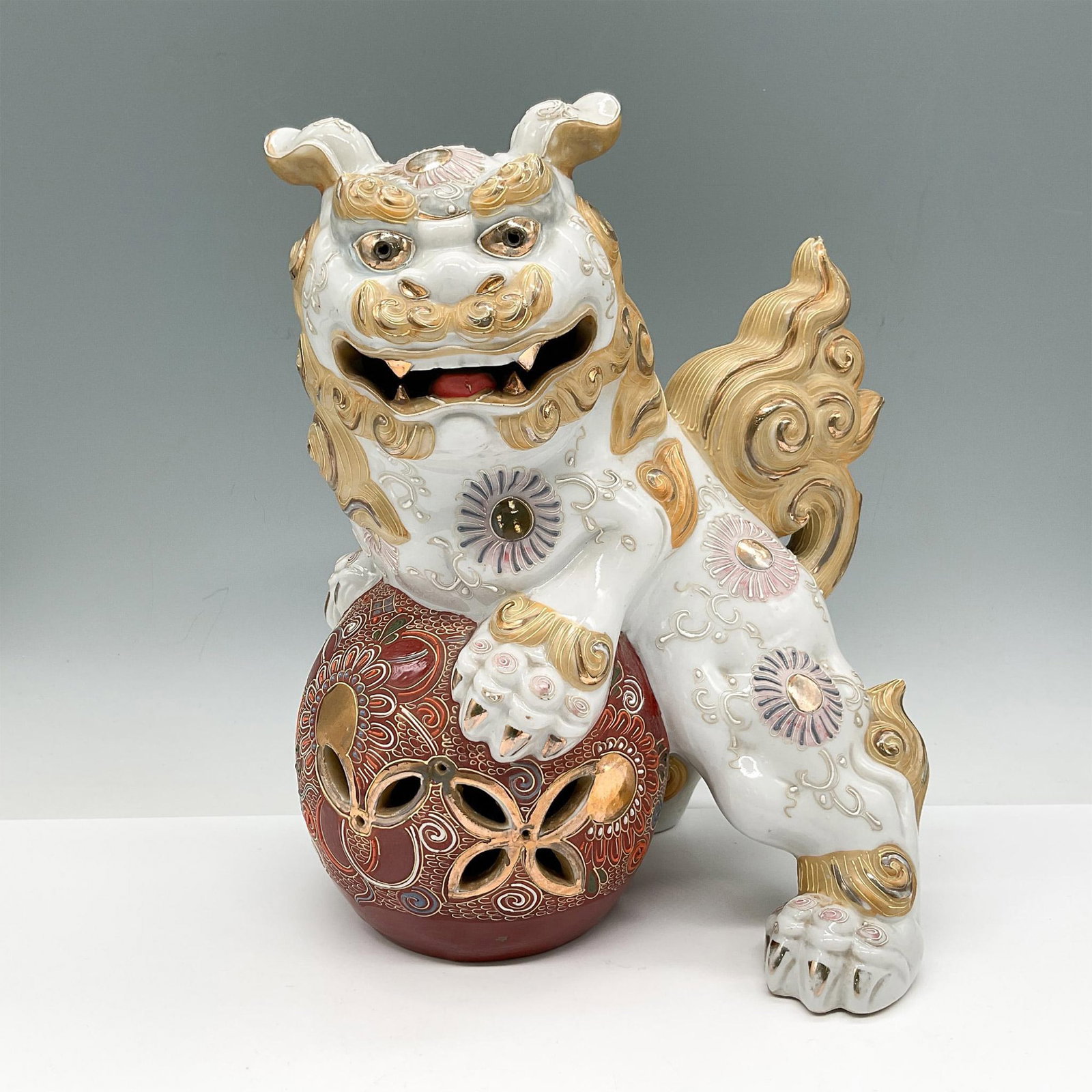 Japanese Kutaniyaki Temple Lion Foo Dog Statue: This beautifully decorated white porcelain ShiShi is enhanced by wind and sun imagery along his body with a fierce protective gaze. Colored in tan, burnt umber, blue and rose with gilt accents through