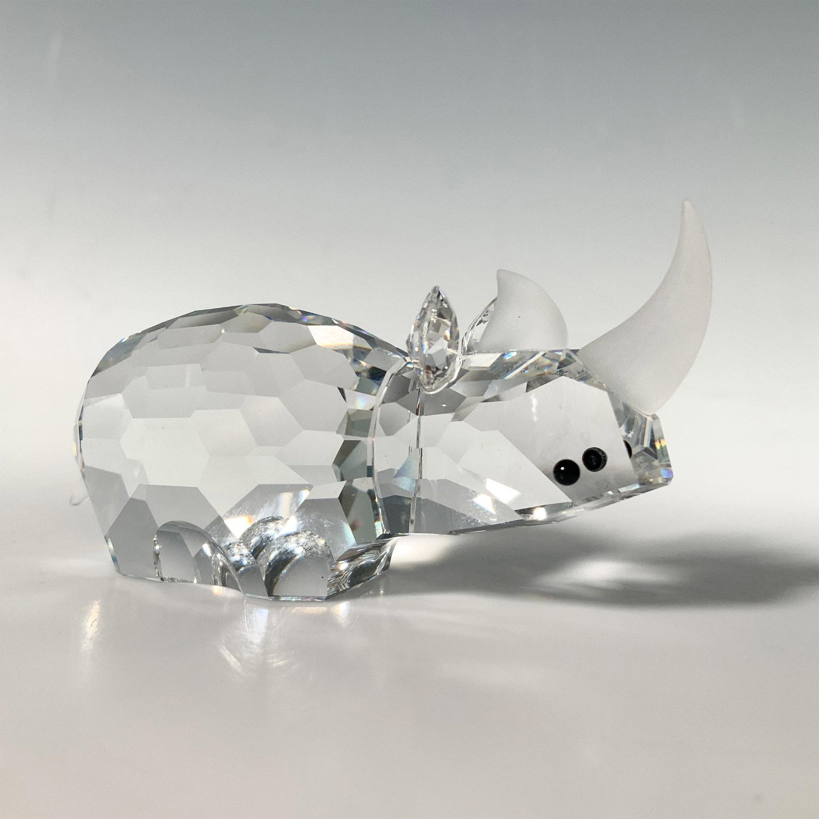 Swarovski Crystal Figurine, Rhinoceros: This rhino figurine is made from clear crystal, with black eyes, and frosted horns and tail. Swarovski acid mark. It comes in its original box which measures 3.25"dia. x 4"H. Artist: Adi Stocker Dimen