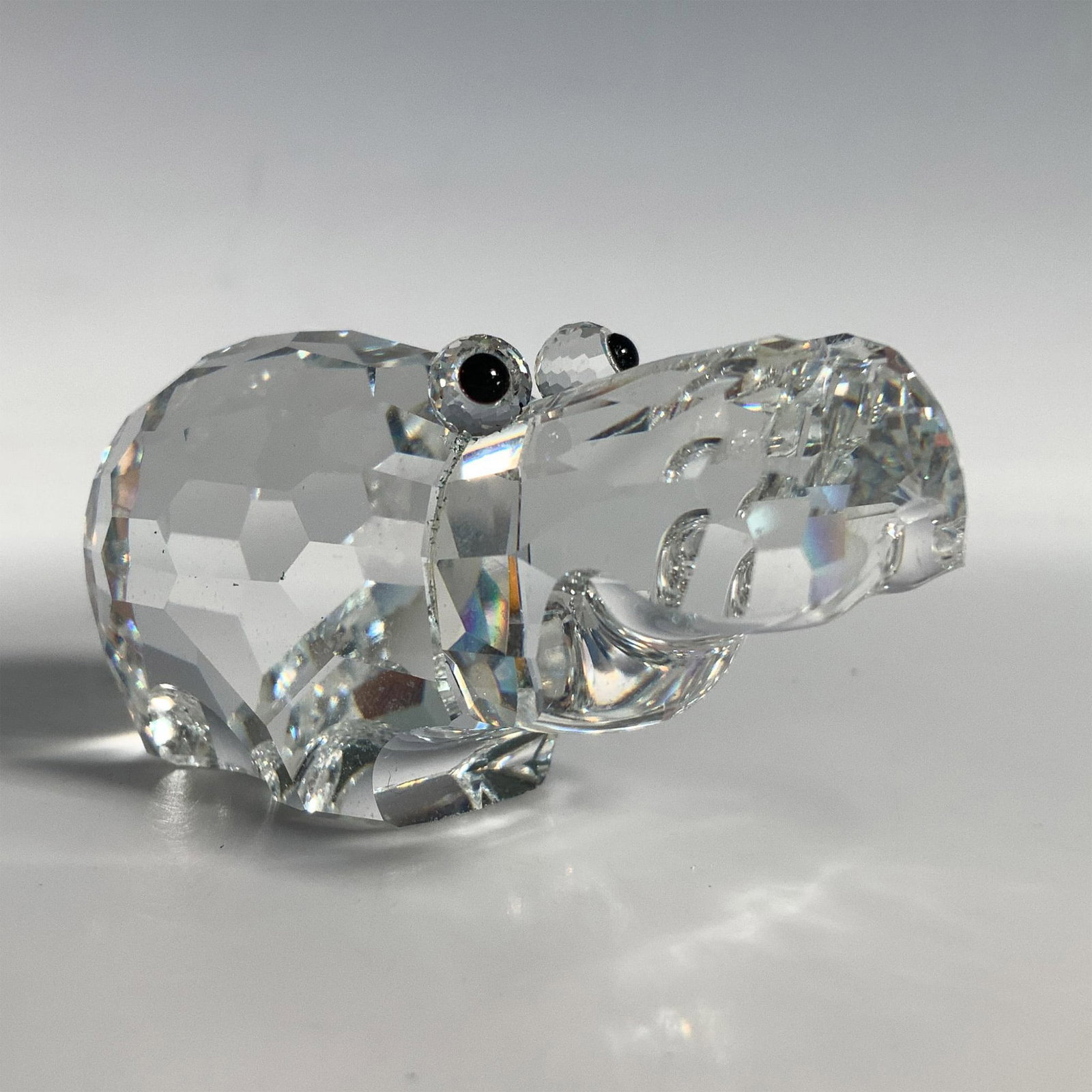 Swarovski Crystal Figurine, Hippopotamus 015187: This retired hippo figurine is made from clear faceted crystal with black eyes and a frosted crystal tail. Swarovski acid mark. It comes in its original box which measures 3.25"dia. x 5"H. Artist: Adi