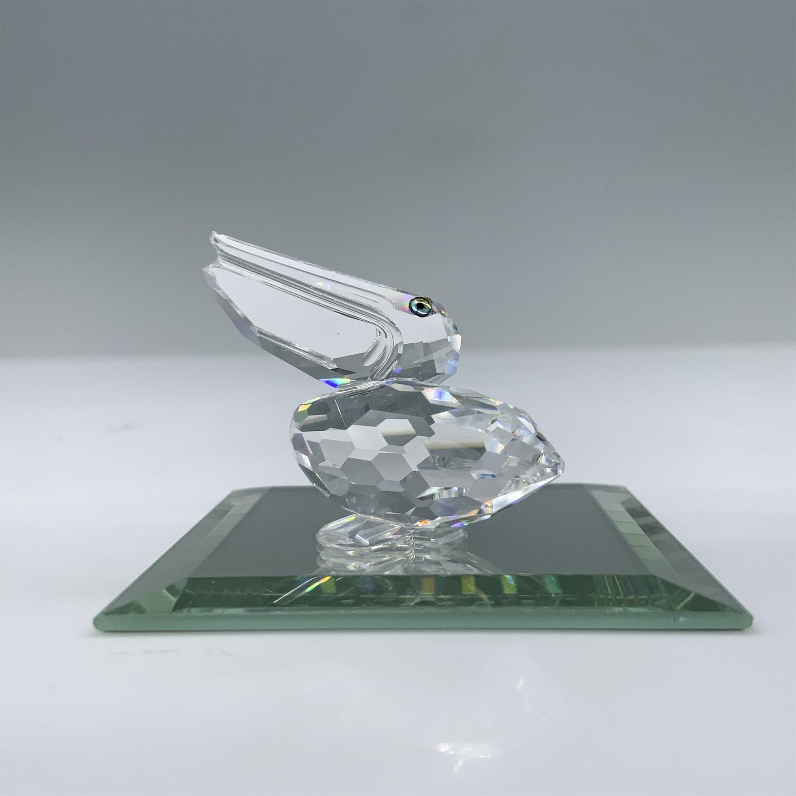 Swarovski Crystal Figurine, Pelican: Introduced for the Feathered Friends theme group this bird features a clear faceted body with blue green eyes. This item has its original box which measures 2.5"H x 3.5"dia. Swarovski swan mark. Inclu