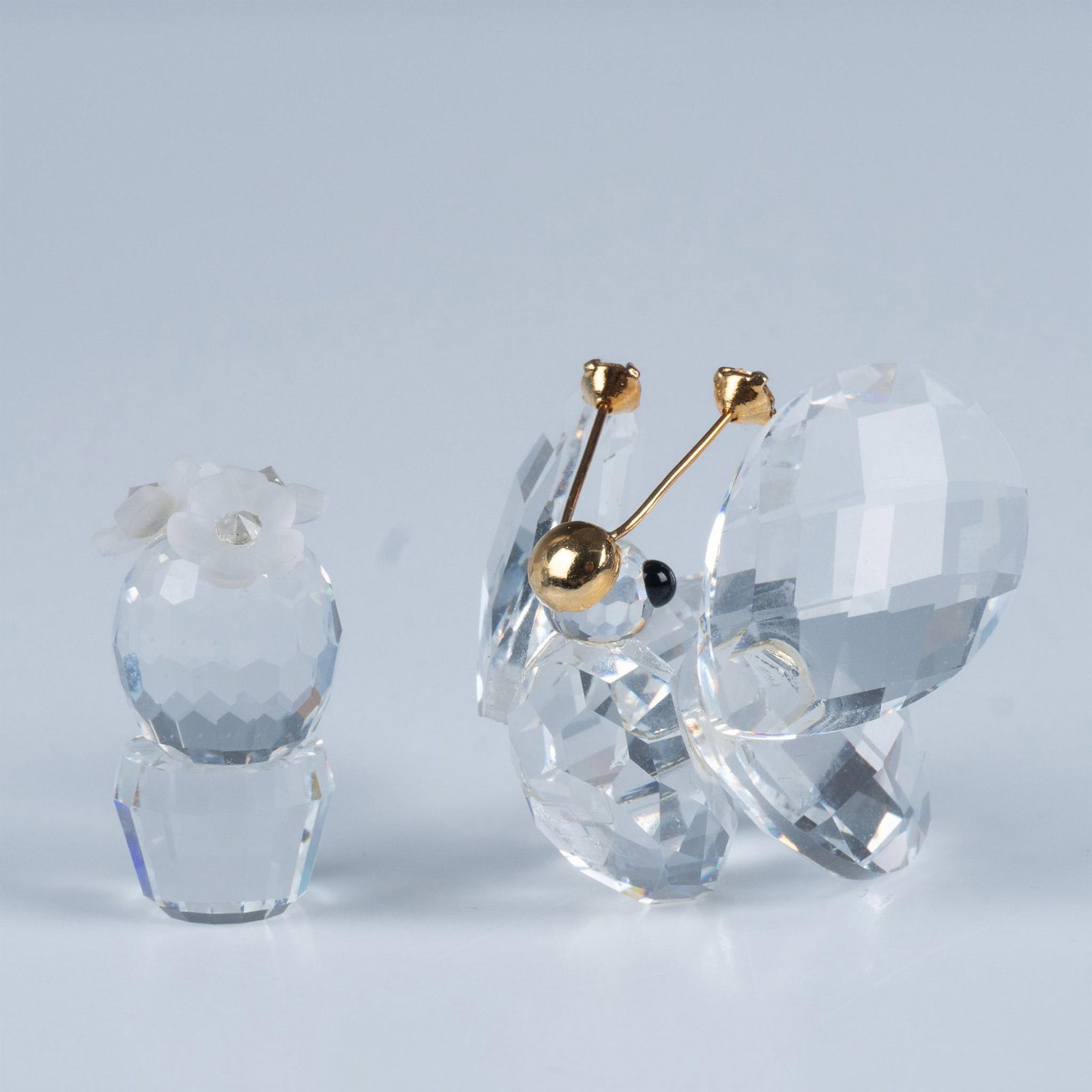 Swarovski Crystal Figurines, Butterfly 7631NR30, Cactus: An enchanting butterfly rests peacefully, adorned with gilded facial accents and sparkling crystals atop its delicate antennas, accompanied by a charming little cactus adorned with frosted flowers in 
