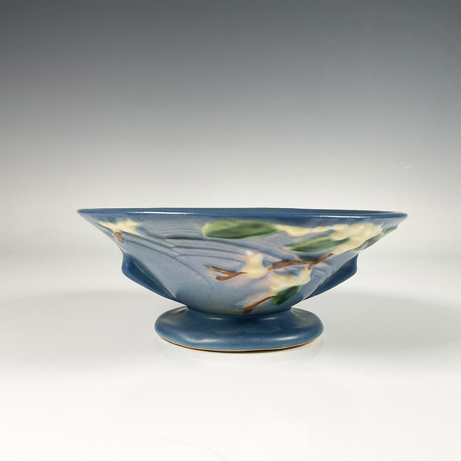Roseville Pottery Bowl, Snowberry: Serene decorative bowl adorned with snowberries on a smooth matte surface in a rich Persian blue color. Roseville mark on the bottom. Issued: 20th century Dimensions: 6.75"W x 2.75"H Manufacturer: Ros
