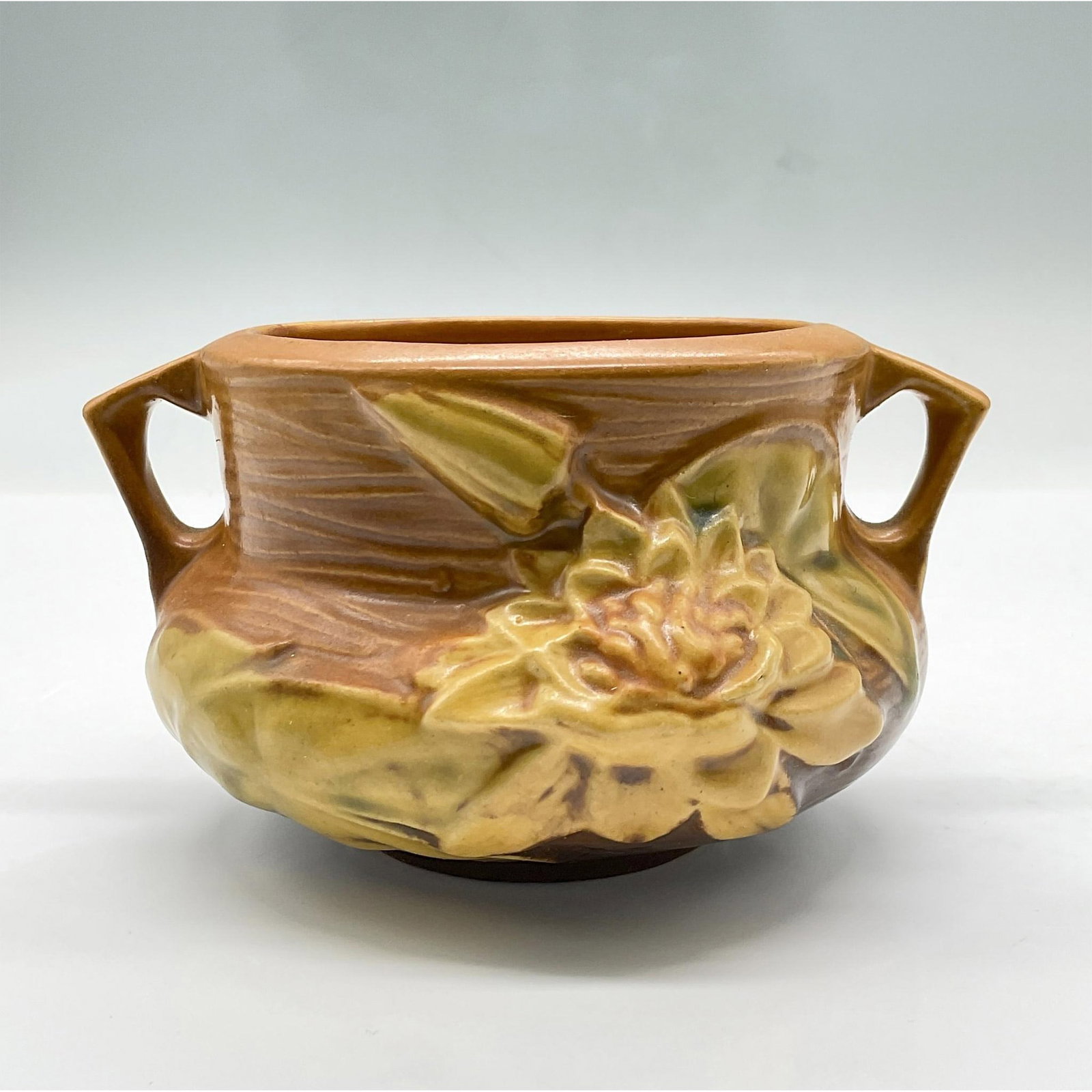 Roseville Pottery, Water Lily Brown Bulbous Planter: Features relief details of a large flower and lily pads over a textured surface. Marked Roseville U.S.A 663. Issued: 1943 Dimensions: 5.25"L x 5"W x 3.25"H Manufacturer: Roseville Country of Origin: U