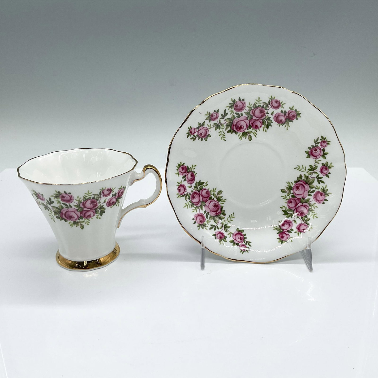 2pc Royal Adderley Bone China Rose Tea Cup and Saucer: English white cup and saucer set adorned with pink roses and gilded trim accents. Royal Adderley backstamps. Cup: 4.25"L x 3.25"W x 3"H. Saucer: 0.75"W x 5.5"H. Issued: 20th century Dimensions: See De
