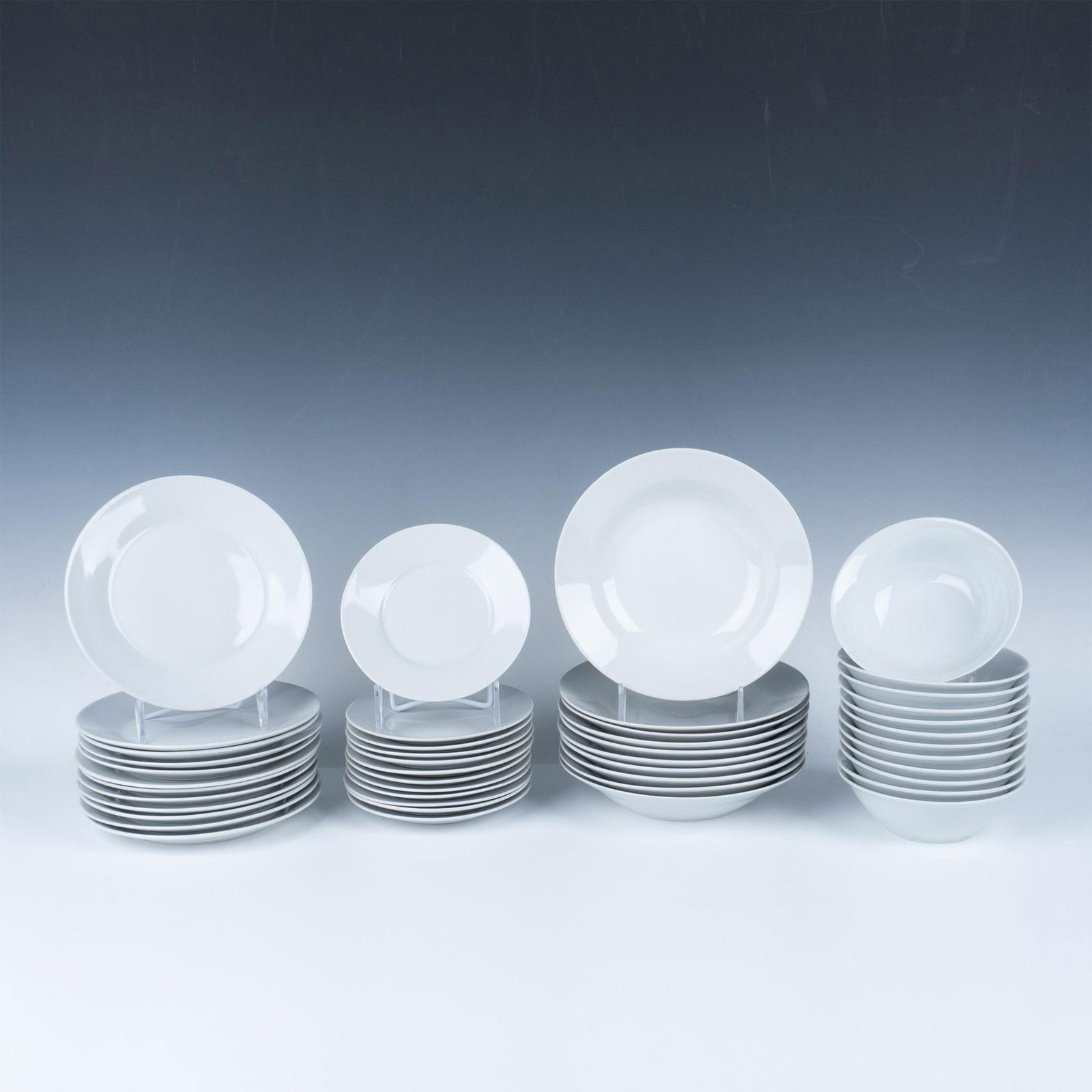 46pc Gibson China Kitchenware Set, Plates and Bowls: A set of 46 white Gibson kitchenware items, including 12 small bowls, 12 salad plates, 12 saucers, and 10 large bowls. Gibson backstamp. Dimensions of the largest item: 1.5"H x 8" dia. Dimensions: See