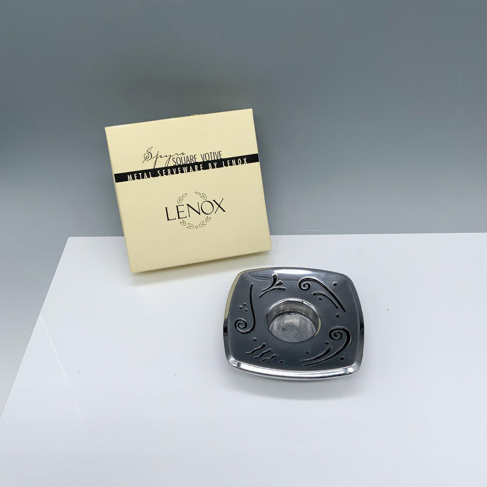 Lenox Spyro Square Votive Metal Serveware: Gorgeous candle holder with fun designs on a metallic looking finish. Lenox backstamp and Spyro sticker. Original candle included. This item has its original box 4.75"L x 4.75"W x 1.25"H. Dimensions: