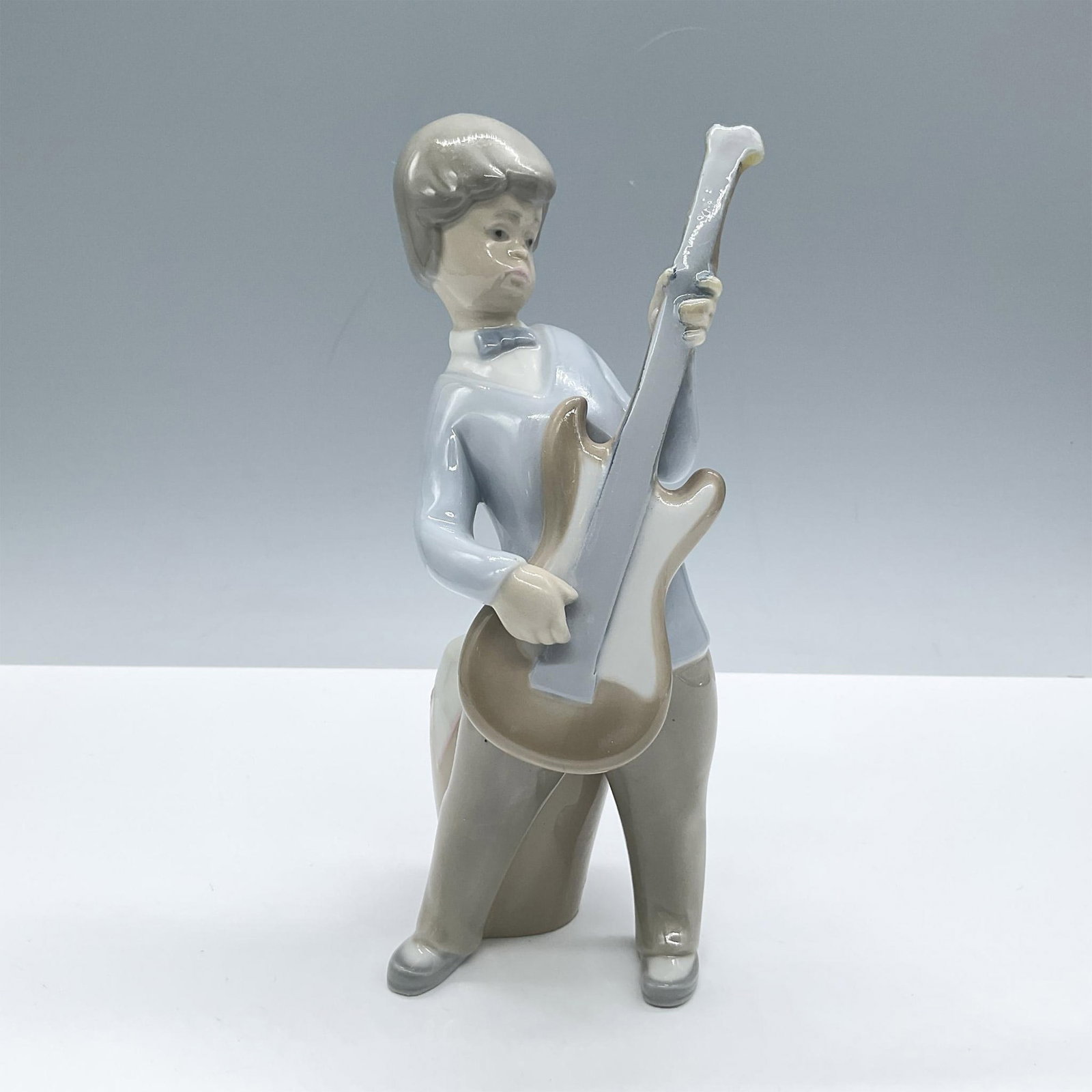 Boy With Guitar 1004614 - Lladro Porcelain Figurine: Glossy finish; Lladro backstamp. Artist: Juan Huerta Issued: 1969 - 1979 Dimensions: 3''L x 3''W x 7.5''H Manufacturer: Lladro Country of Origin: Spain