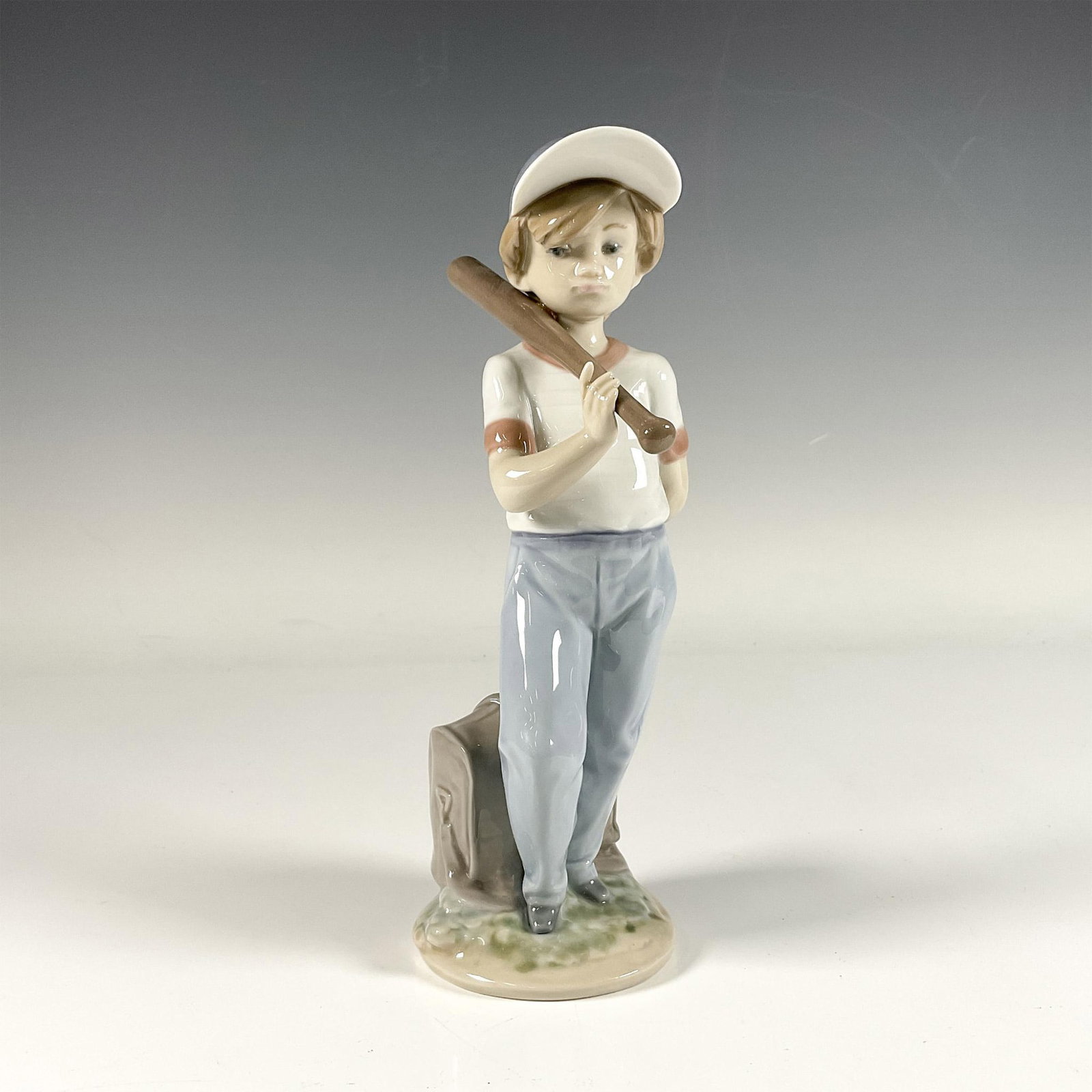 Can I Play 1007610 - Lladro Porcelain Figurine: Glossy figure of an adorable boy with a baseball on his shoulder, adorned in serene color tones. Lladro backstamp. This item includes an original box: 5.75"L x 5"W x 11"H. Artist: Antonio Ramos Issued
