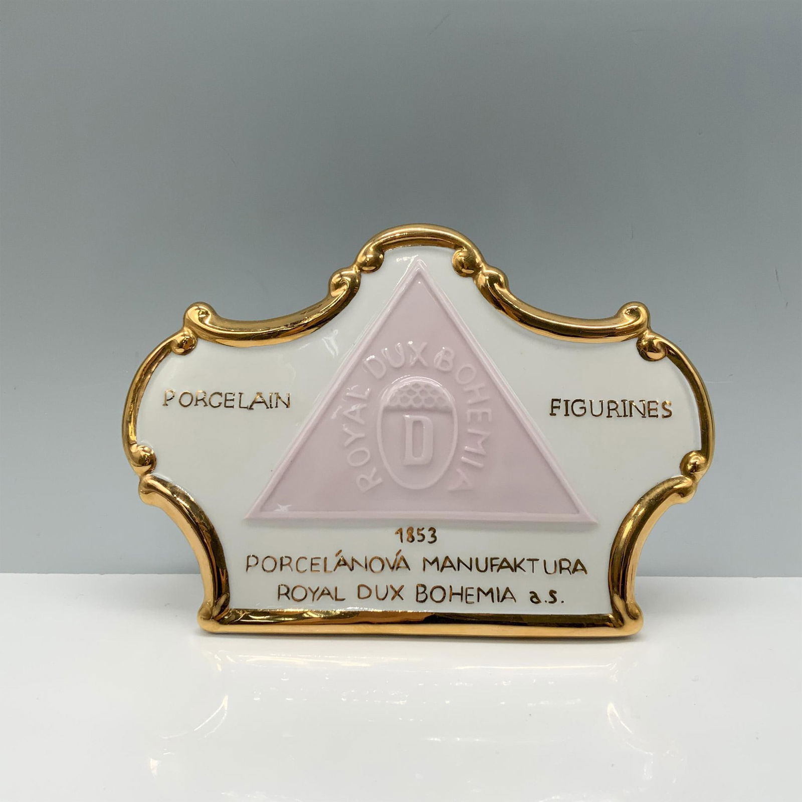 Royal Dux Bohemia Porcelain Figurines Plaque: Delightful crown shaped figure with gilded edges and markings featuring the Royal Dux Bohemia mark. Issued: 20th century Dimensions: 6"L x 1.5"W x 4"H Manufacturer: Royal Dux Country of Origin: Czech