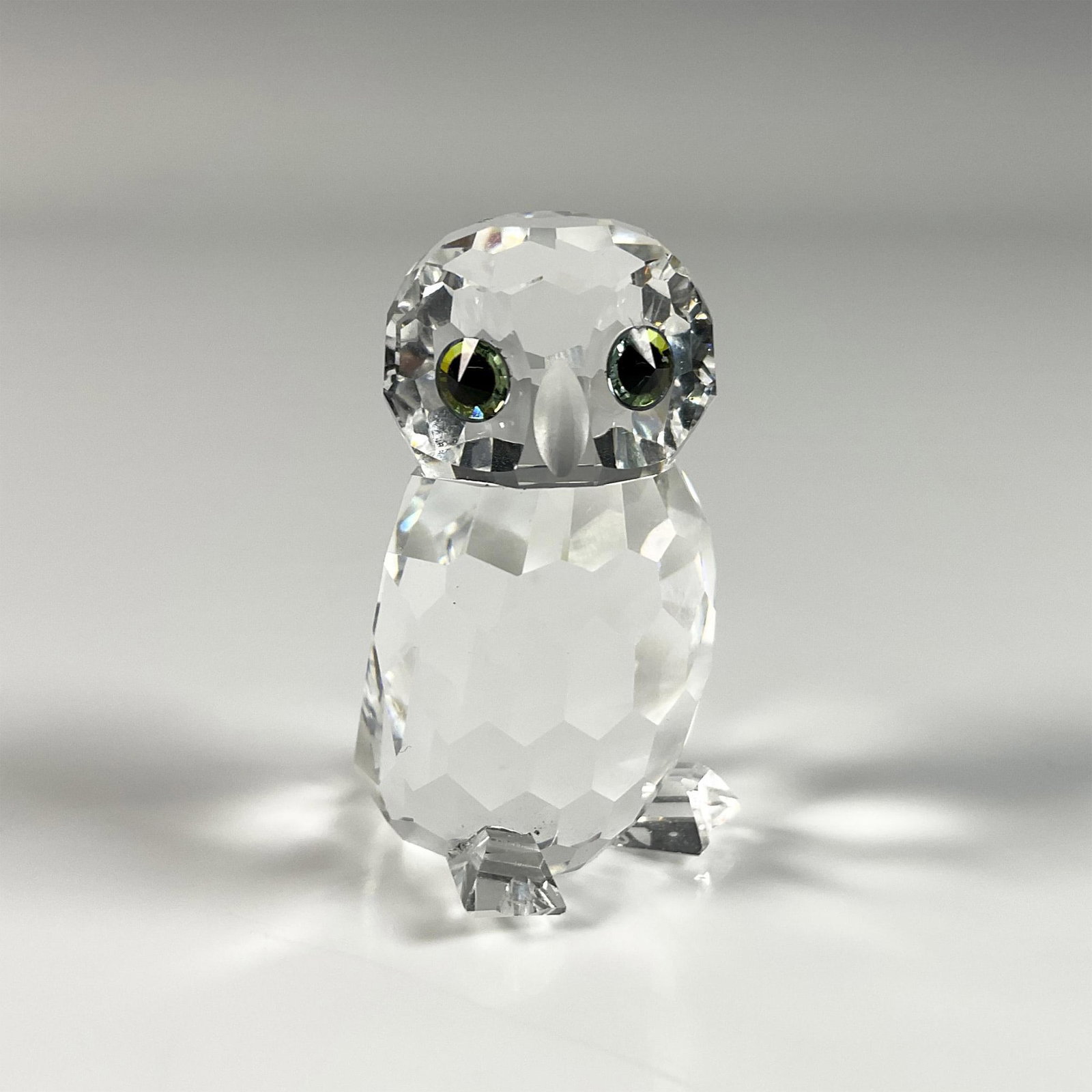 Swarovski Crystal Figurine, Owlet: Elegant clear crystal owl figure from Woodland Friends series, featuring green accents on its eyes and a frosted crystal beak and feet. Swarovski swan mark. This item includes an original box: 3.25"W 