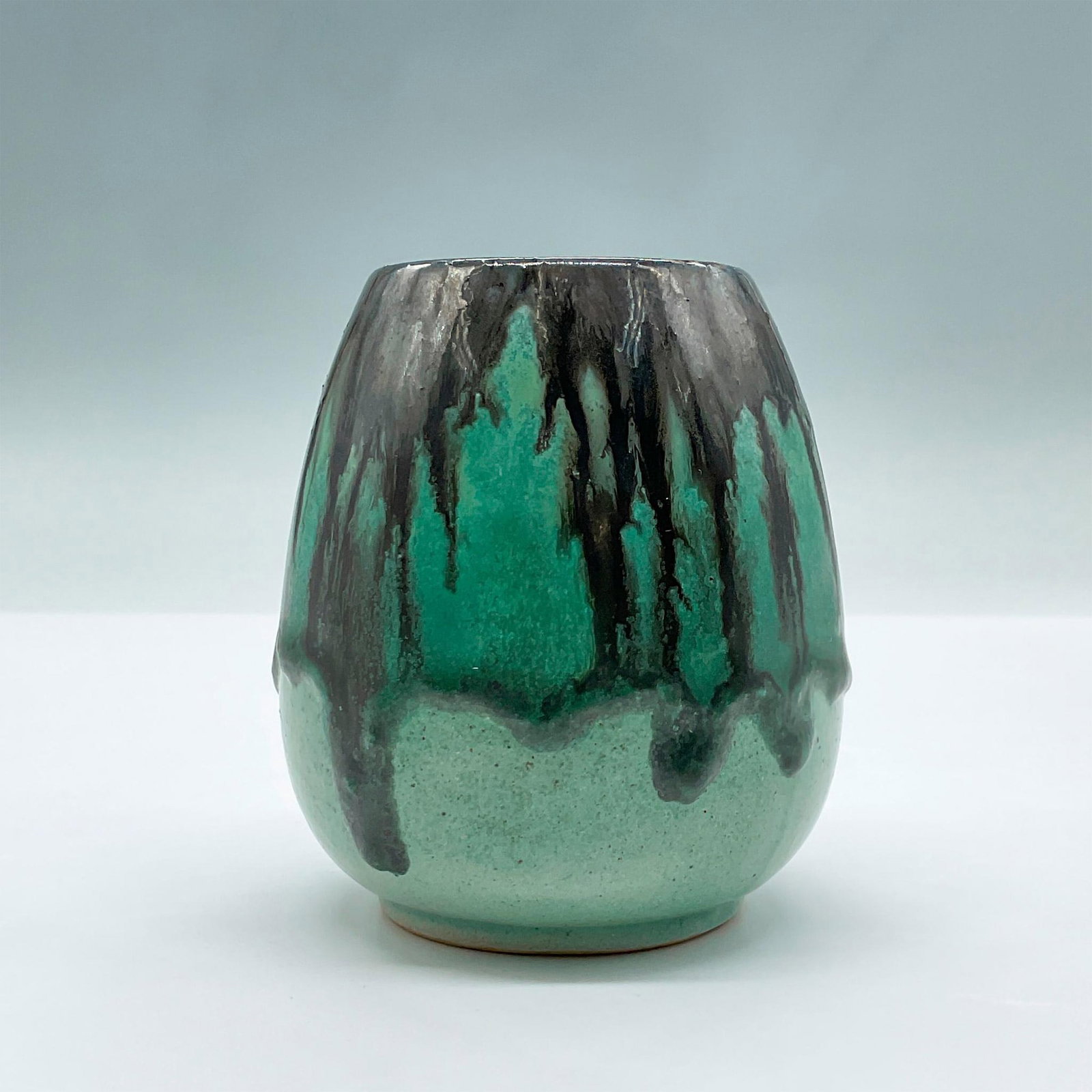 Fulper Art Pottery Vase: This exquisite ceramic vase showcases a dripping black and green glaze over a light green base. Faded makers mark stamped to the underside. Issued: 20th century Dimensions: 3.5"L x 3.5"W x 4"H Manufac