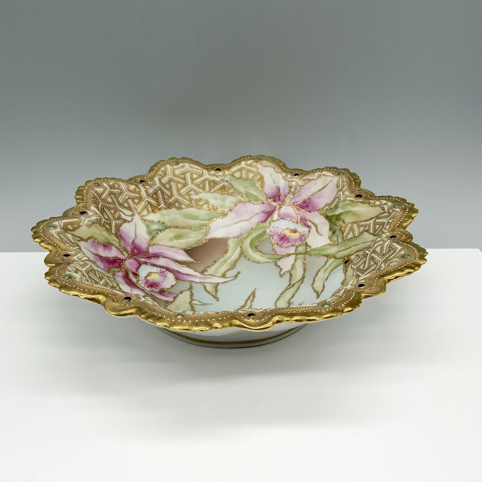 Nippon Porcelain Scalloped Edge Orchid Bowl: Gorgeous hand painted moriage slip bowl with beading and decorated with large flowers. Issued: 20th century Dimensions: 11"L x 11"W x 2.75"H Manufacturer: Nippon Country of Origin: Japan