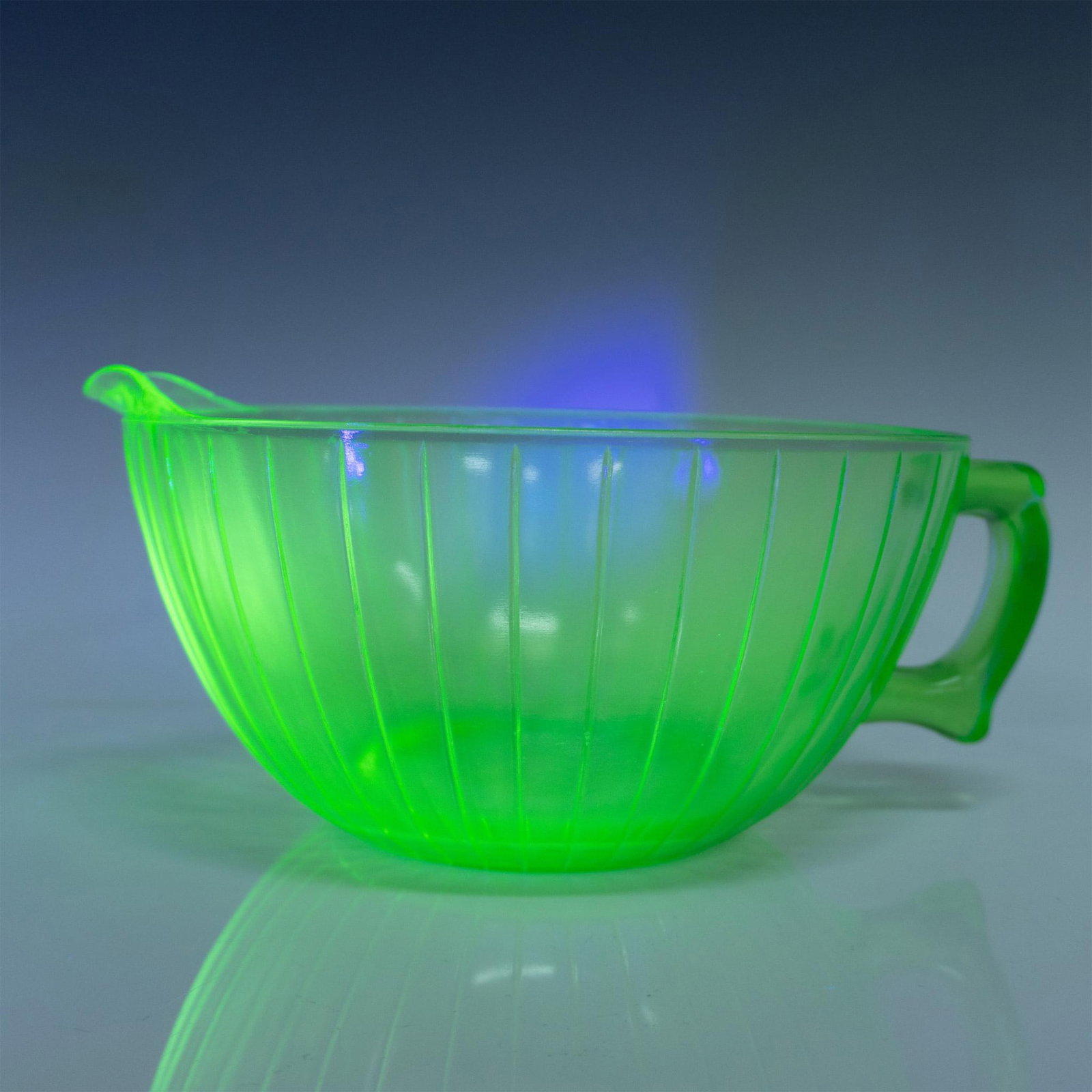 Vintage Uranium Glass Mixing Bowl With Handle And Spout: Green Uranium depression glass bowl lined with ridges. Has a sturdy handle and a spout for pouring. Dimensions: 10.75"L x 9"W x 4.25"H