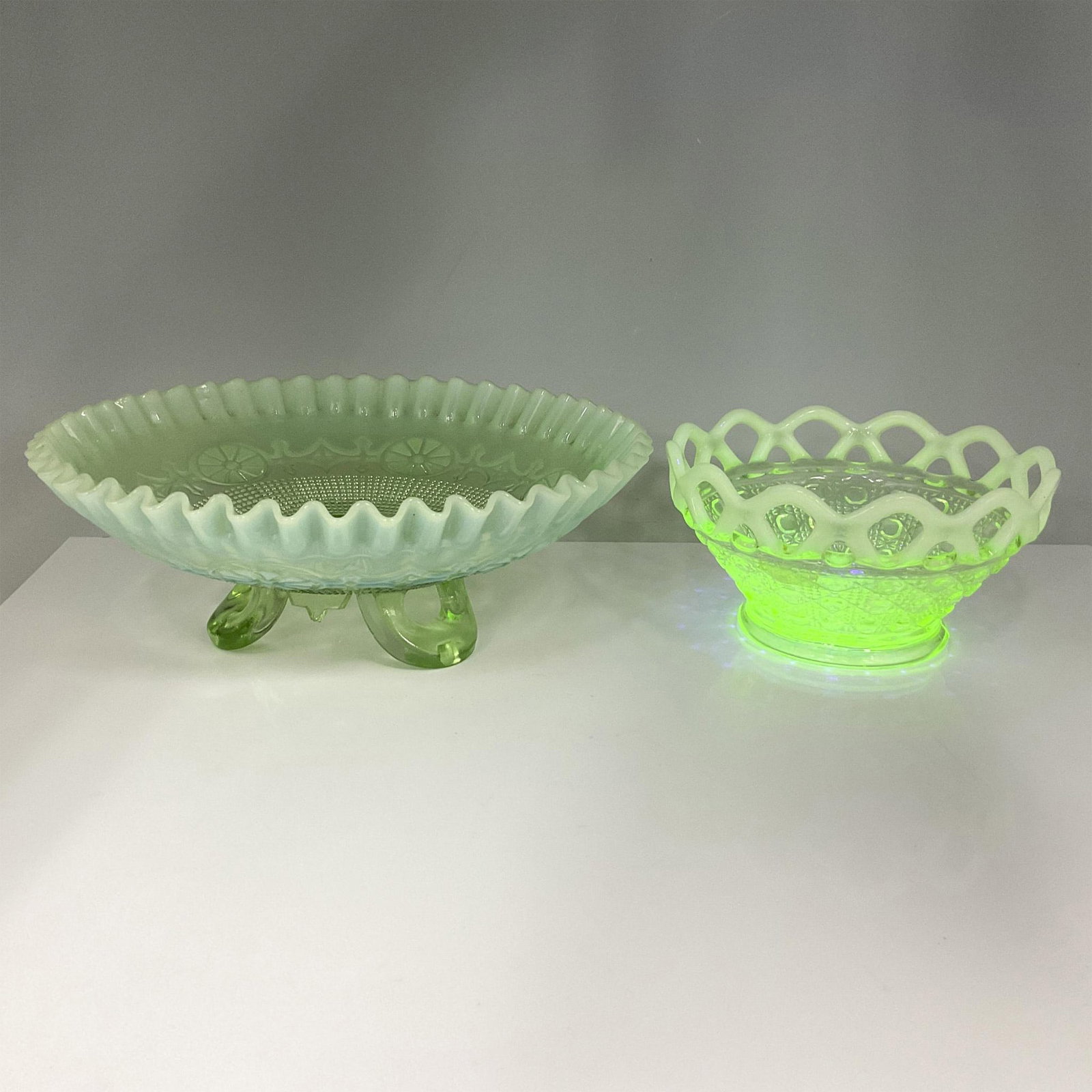 2pc Vintage Uranium Glass Candy Bowls: A beautiful Art Deco-inspired duo featuring a large piece with an ornate, scalloped edge design, complemented by a smaller candy bowl with a delicate lace edge. Both pieces showcase a striking green h