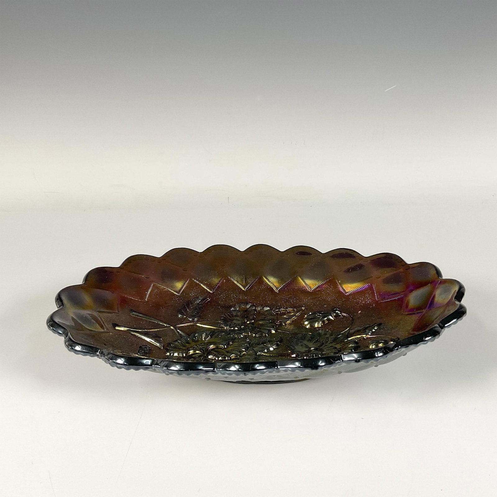 Carnival Glass Candy Bowl: Carnival glass bowl with a rainbow like sheen, adorned with floral patterns and a decorative rim. Dimensions: 9"L x 6"W x 1.75"H