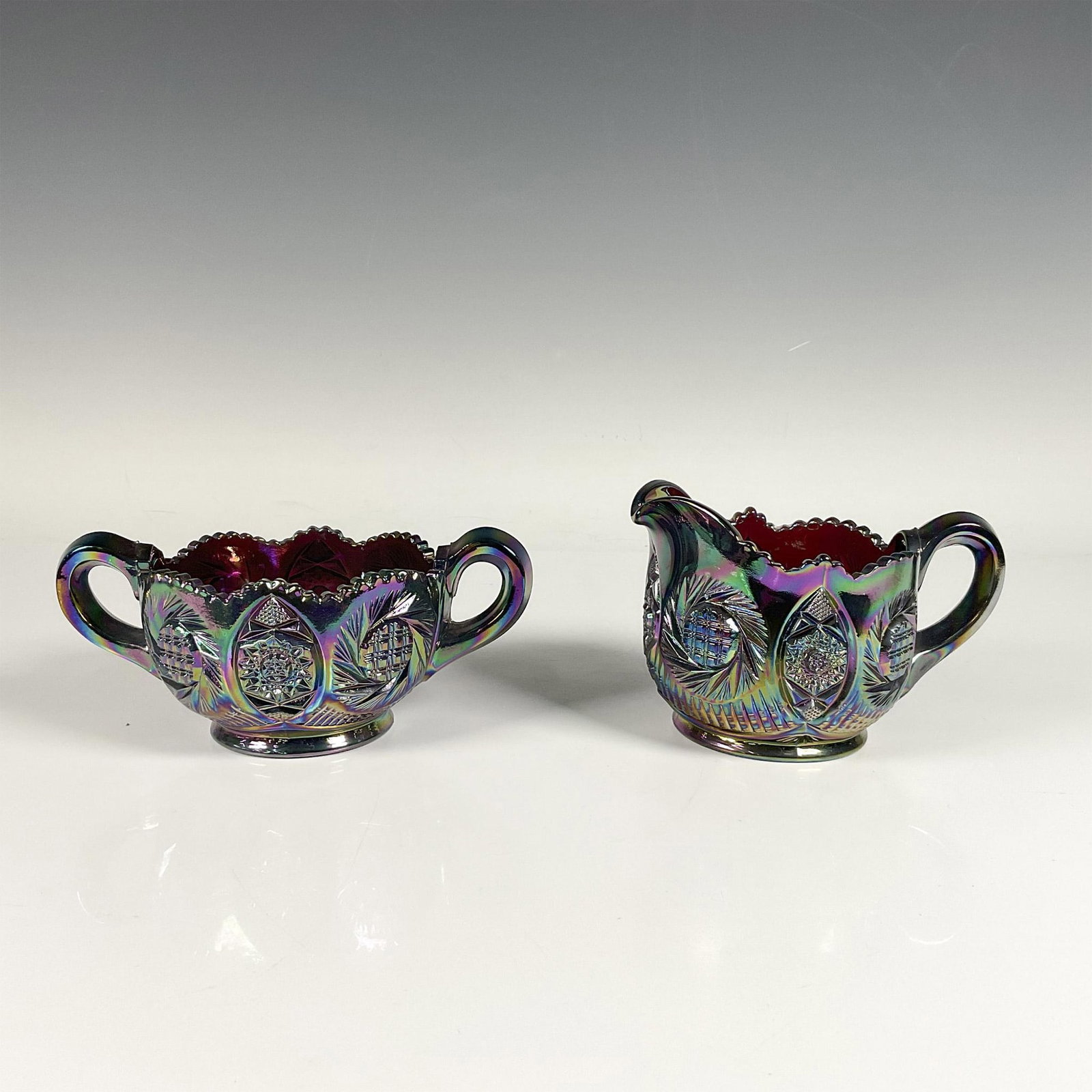 Carnival Glass Sugar Bowl and Creamer: Set of two iridescent carnival glass pieces featuring beautiful Sunburst pattern. Sugar bowl with a lid: 6.5"L x 4"W x 2.75"H. Creamer with a lid: 5.5"L x 4"W x 3.75"H. Dimensions: See Description