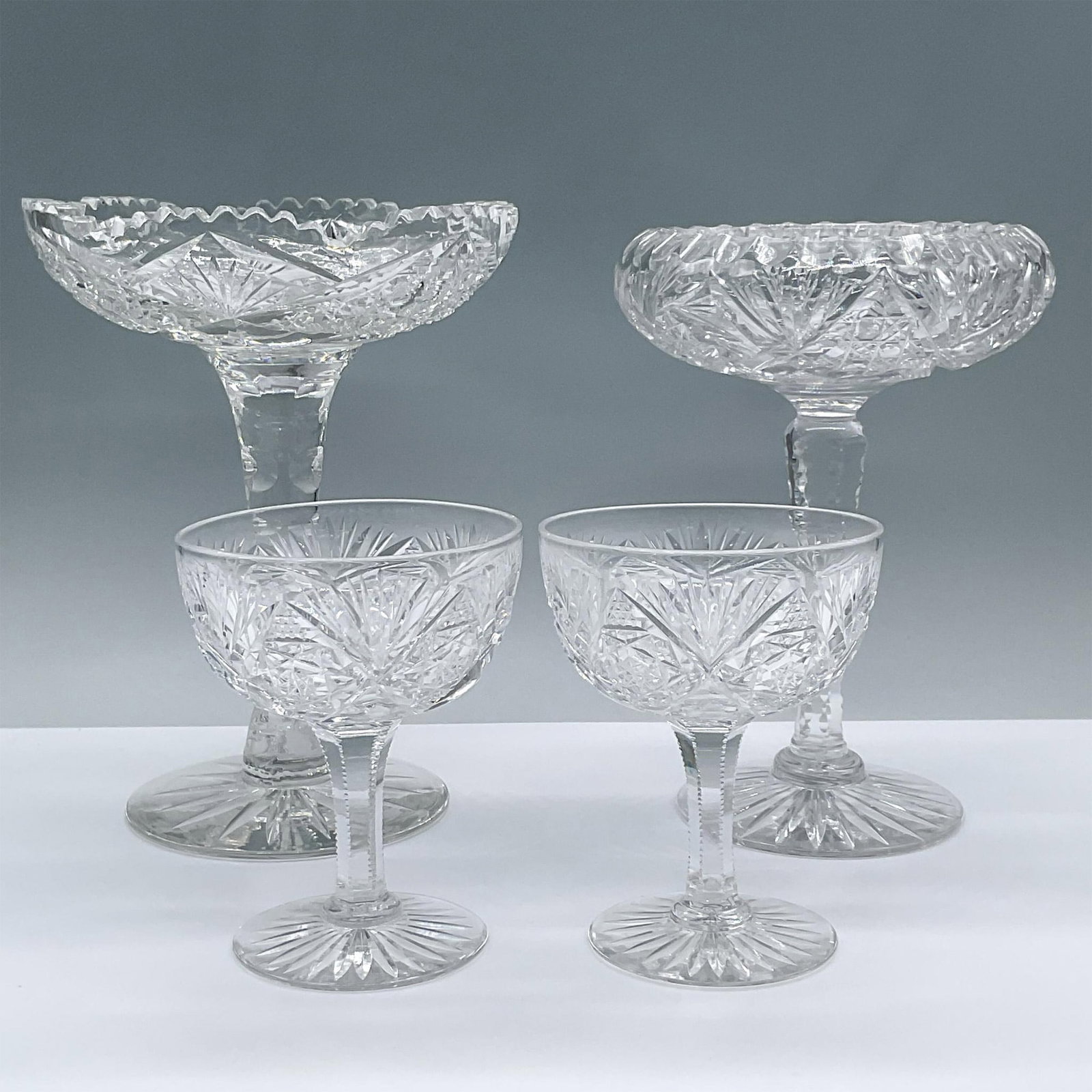 4pc Glass Pedestal Bowls and Sherbet Glasses: This brilliant cut glass 4 piece includes a tall pedestal bowl with a hobstar cane and saw tooth design, a tall compote with a pinwheel pattern and two sherbet glasses. Largest measures 6"L x 6"W x 7.