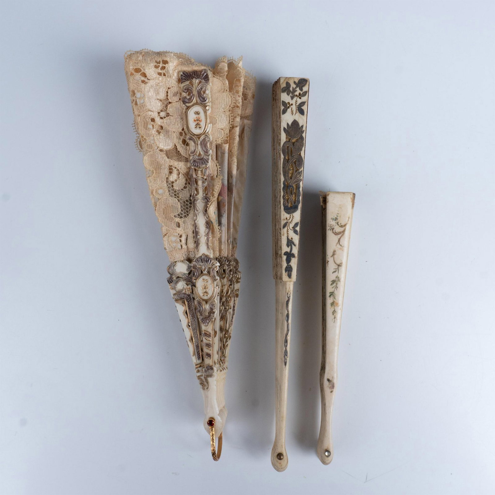 3pc Vintage Hand Fans: A stunning set of three hand fans, the first adorned with lace and featuring a charming scene of Victorian figures at leisure, the second depicting a Victorian couple in a field, with the man presenti