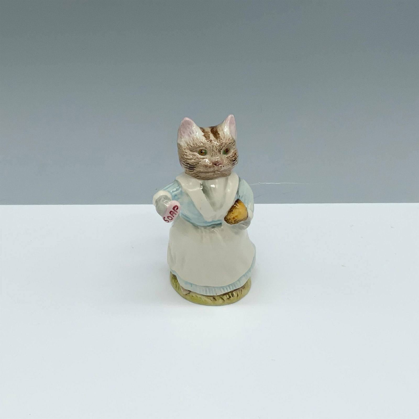 Royal Albert Beatrix Potter Figurine, Tabitha Twitchit: Glossy porcelain figure of a cat holding a bar of soap. Royal Albert Beatrix Potter backstamp. This item has its original box (2.5"L x 2"W x 5"H). Issued: c. 1989 Dimensions: 2.25"L x 2.5"W x 3.5"H Ma