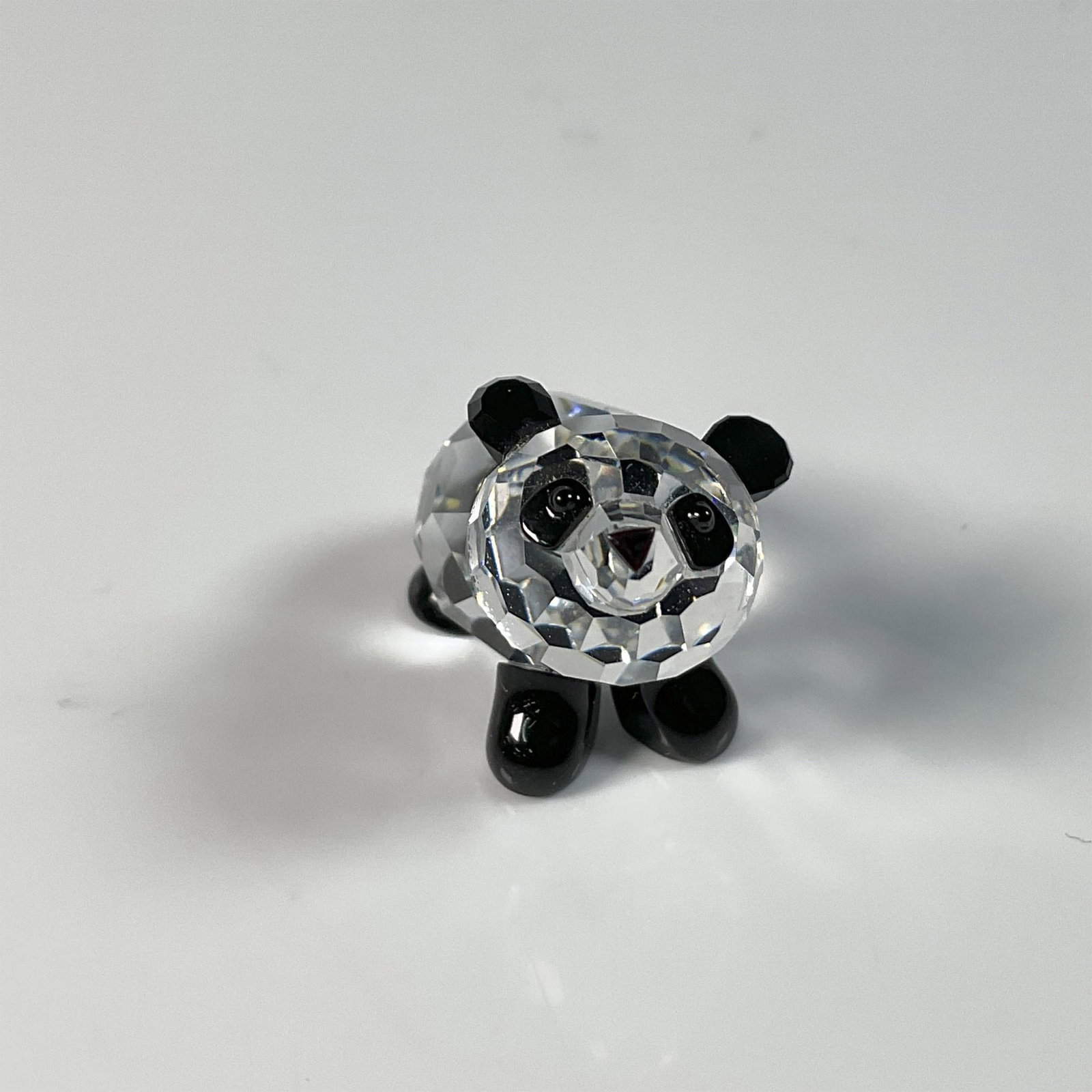 Swarovski Crystal Figurine, Panda Baby: Adorable baby panda figure in a playful pose trying to stand somehow, with black accents on its ears, eyes, and legs. Swarovski swan mark. This item includes an original box: 3.25"W x 2.5"H. 181081. A