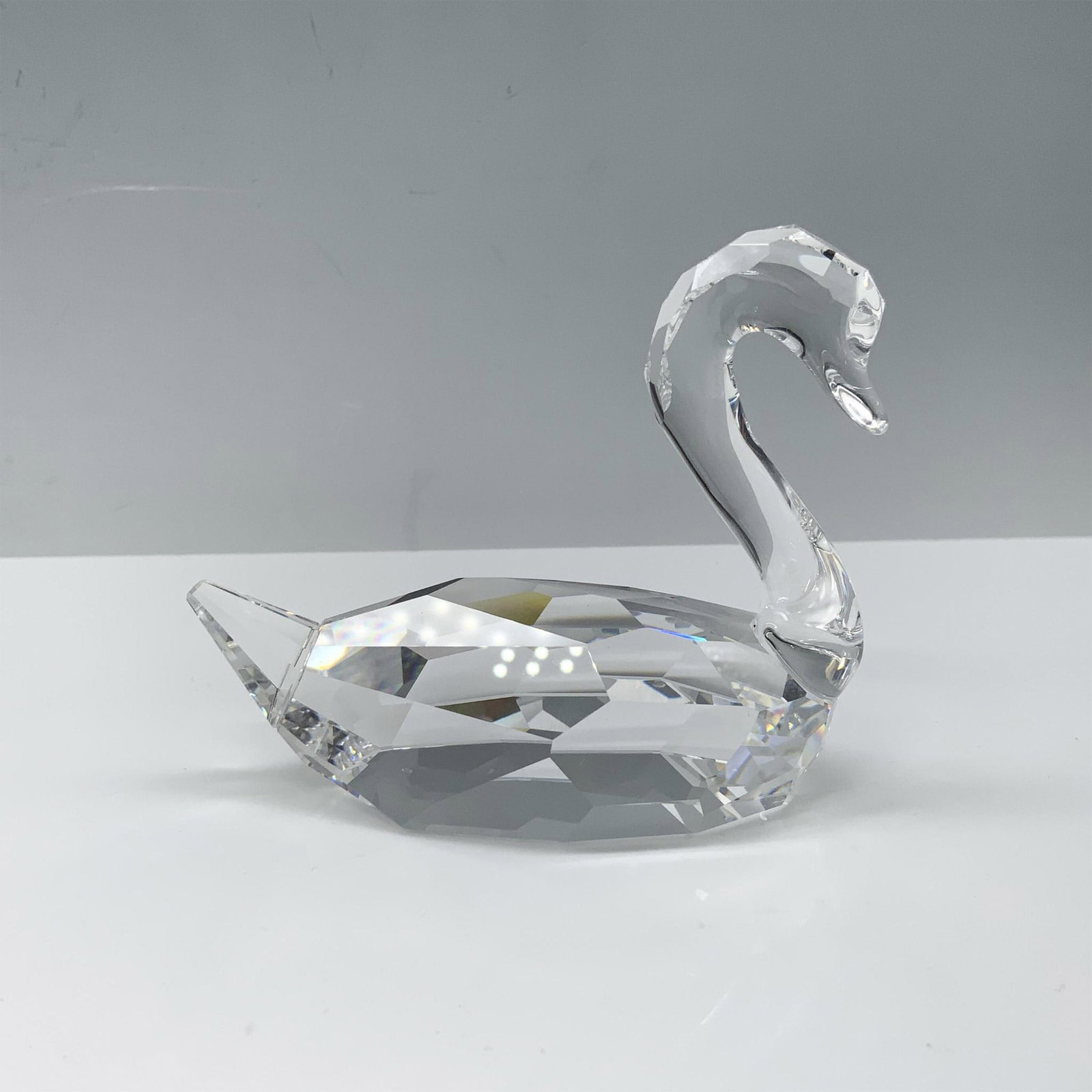 Swarovski Crystal Figurine, Swan Flirting 844168: Lovely figure of a crystal swan with its head turned to the side. Swarovski backstamp. This item has its original box 5.75"L x 3.75"W x 5.75"H. Certificate of Authenticity included. Artist: Anton Hirz