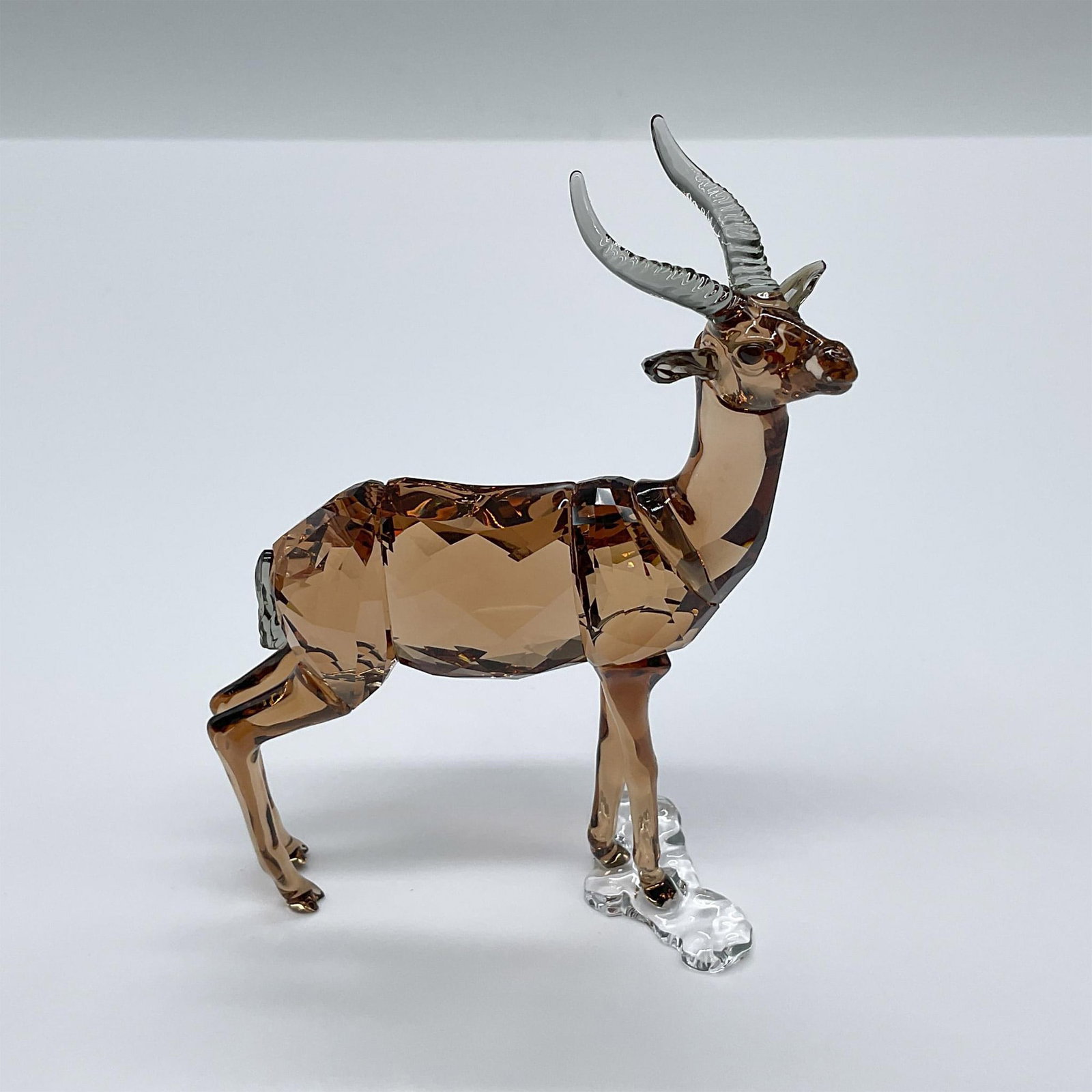 Swarovski Crystal Society 2018 Figurine, Gazelle: A stunning light brown crystal gazelle with smoky-grey antlers. Swarovski swan mark. This item has its original box: 6"L x 6"W x 4"H. Artist: Martin Zendron Issued: 2018 Dimensions: 3.25"L x 1.25"W x 