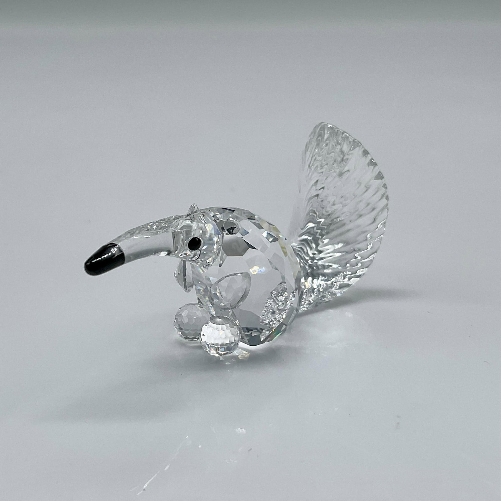 Swarovski Crystal Figurine, Anteater: Miniature clear crystal figure has faceted body, black crystal eyes and nose with etched crystal tail. Swarovski backstamp. 271460. This item has its original box 2.5"H x 3.25" dia. Artist: Adi Stocke