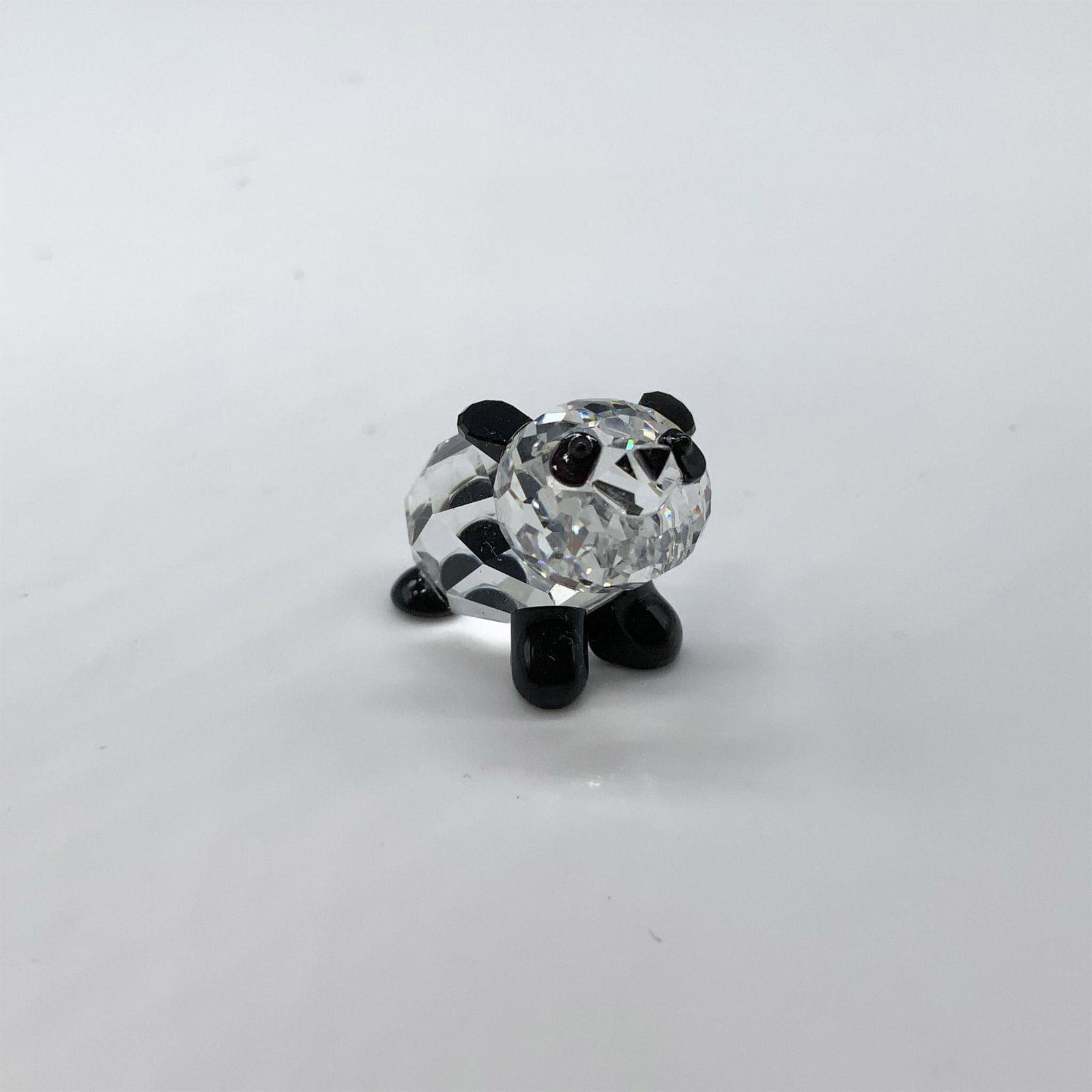Swarovski Crystal Figurine, Baby Panda: Beautiful miniature of a perfectly crafted baby panda with his paws, ears and eye in black crystal. Swarovski swan mark. This item has its original box. Box measures: 2.5"H x 3.25" dia. 181081. Artist