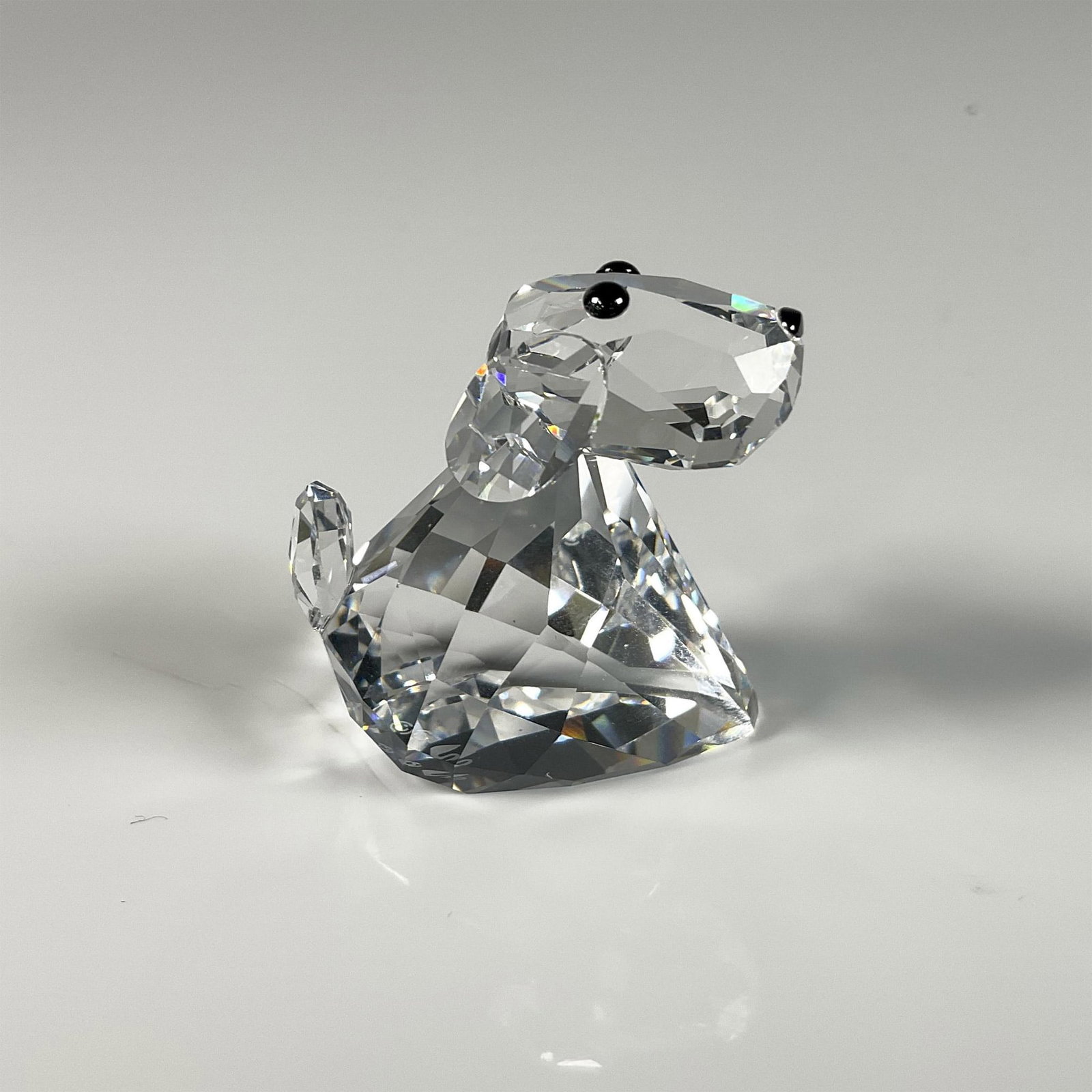 Swarovski Crystal Figurine, Lovlots Pioneers-Robby B Dog: Clear crystal dog called Robby B, featuring black eyes that symbolizes its loyal character. Swarovski swan mark. This item includes an original box: 3.25"W x 2.5"H. 840908. Artist: Elke Kumar Issued: 