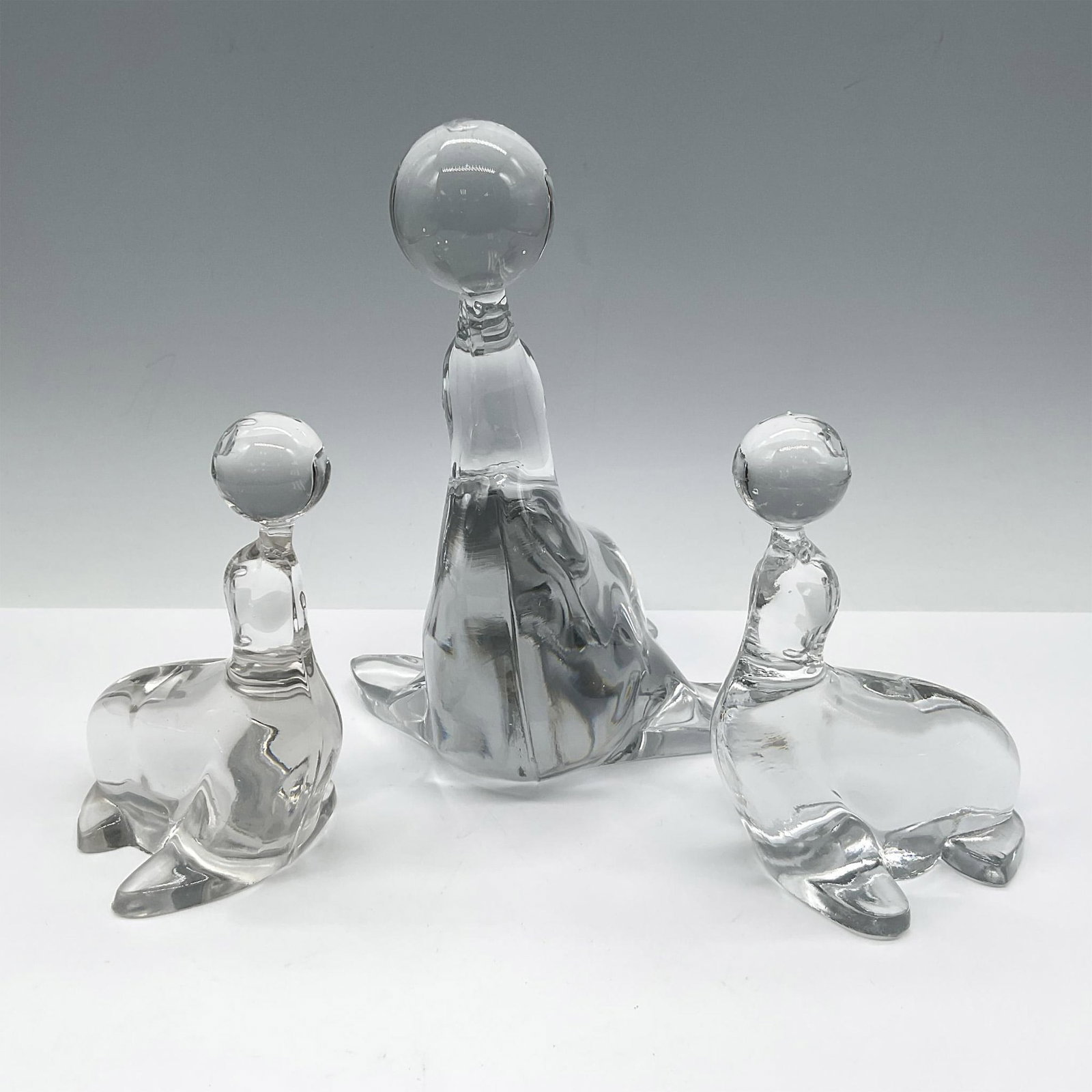 3pc Art Glass Seal Figurines with Balls: Simply lovely design of glass figures representing adult and babies balancing balls on their noses. Unmarked. Largest piece 6.25"L x 5.75"W x 7"H. Issued: 20th century Dimensions: See Description