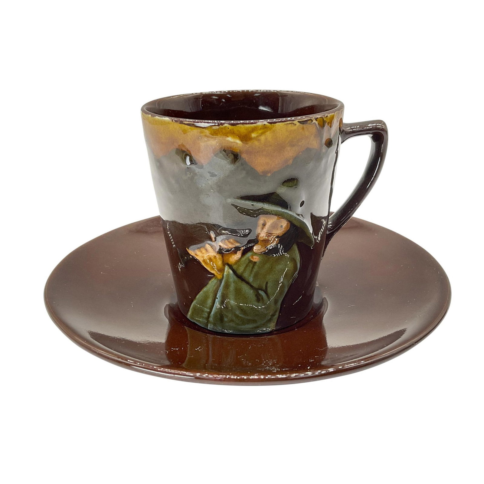 Royal Doulton Kingsware Cup & Saucer, Pied Piper: Kingsware in luscious brown glaze, this cup features the pied piper in high relief on the front with matching saucer. The cup measures: 3.25"L x 2.5"W x 2.75"H. The saucer: 5.25"Dia. Royal Doulton bac