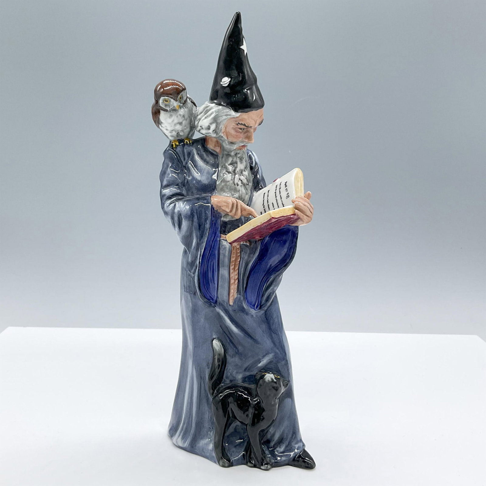 Wizard - HN2877 - Royal Doulton Figurine: Modeled in deep blue hues, accompanied by an owl and a black cat. Royal Doulton backstamp. Artist: Alan Maslankowski Issued: 1979 - 2006 Dimensions: 3.5''L x 2.5''W x 9''H Manufacturer: Royal Doulton