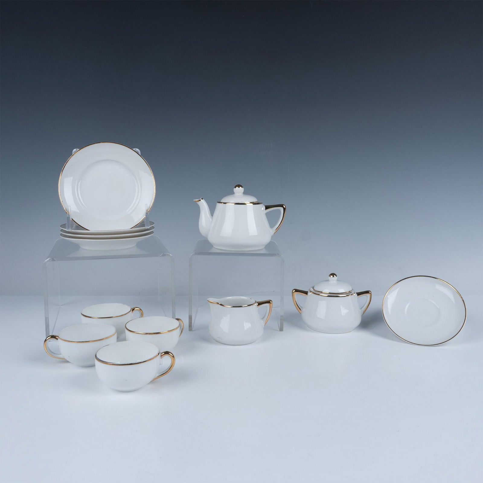 15pc Okwan China Gold Trim Miniature Tea Party Serveware: A classic miniature set consisting of four tea cups with their accompanying saucers, four dessert plates, a tea pot, creamer, and sugar bowl with lid, all adorned with delicate gilt embellishments. Ok