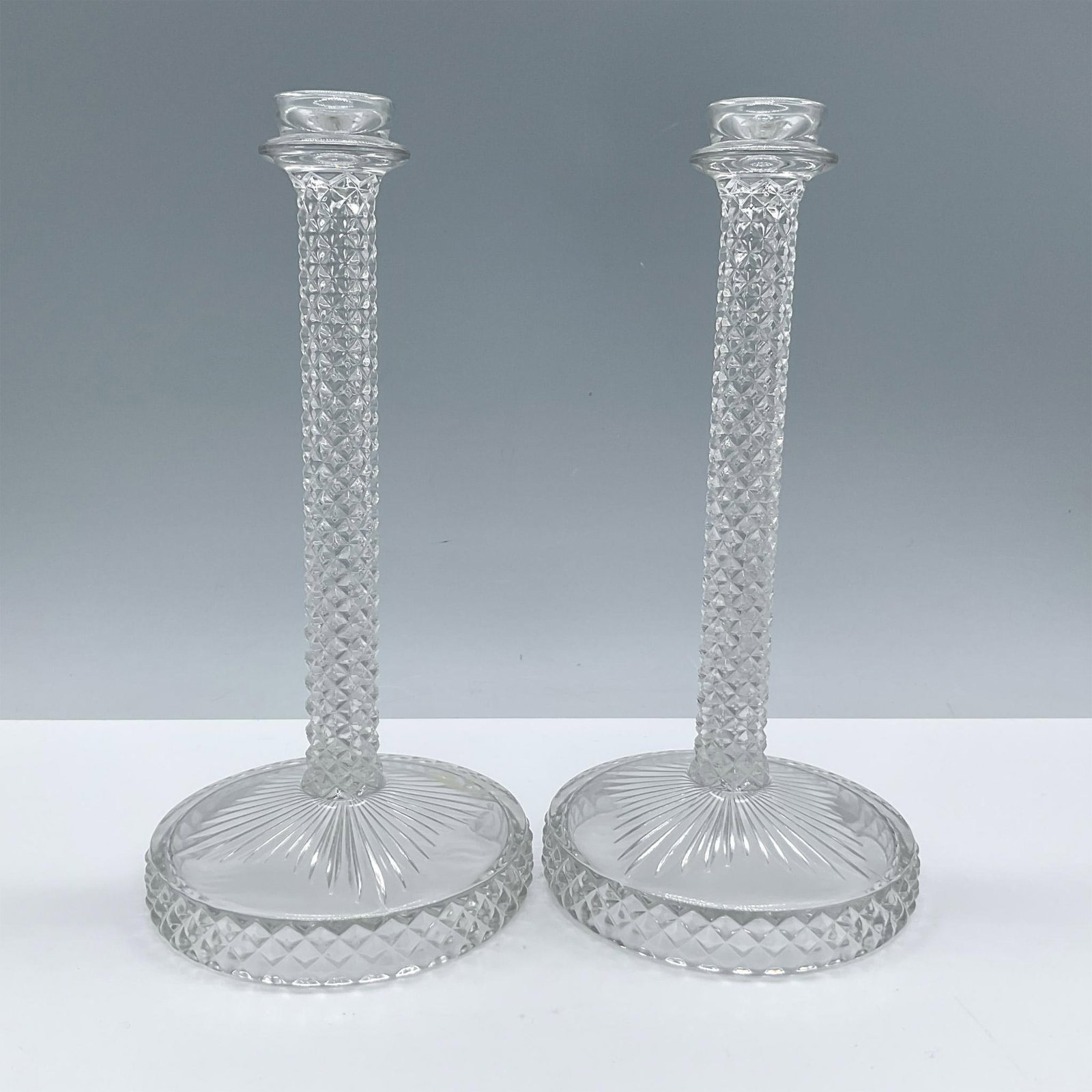 Pair of Vintage Glass Taper Candleholders: Beautiful clear glass with an elegant vintage design. The stem features a textured diamond pattern and the base a beautiful starburst design. Each piece measures: 8.5''H x 4''dia. Issued: 20th century