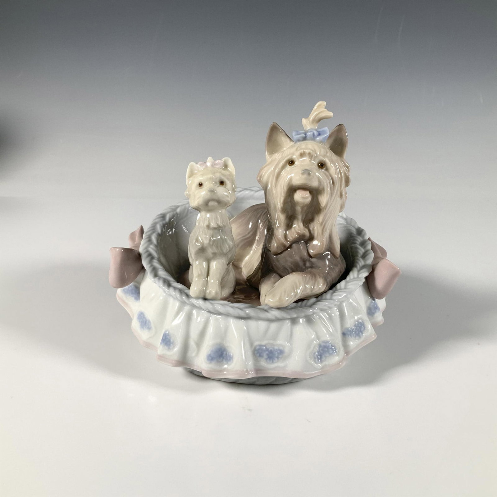 Our Cozy Home 1006469 - Lladro Porcelain Figurine: A glossy figure of two cute dogs sitting in a bed. Lladro backstamp. Signature and date on base. Lladro backstamp. This item has its original box: 7.25"L x 6.75"W x 5.75"H. Artist: Jose Luis Alvarez I