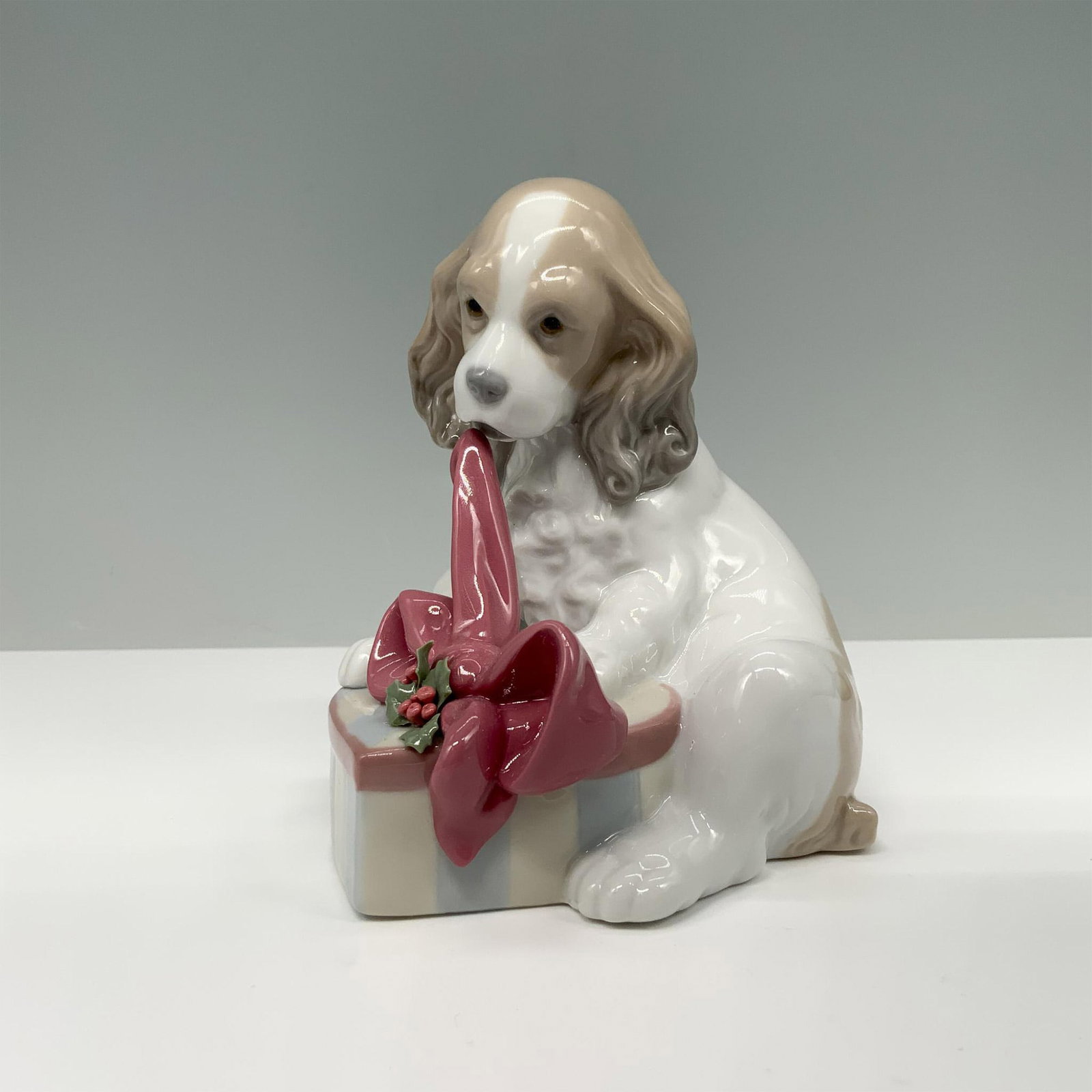 Lladro Porcelain Figurine, Cant Wait Christmas 01008692: Glossy finish. Figure of a puppy with a red ribbon, sitting next to a gift box. Lladro backstamp. This item has its original box. Box measures: 8.25"L x 5.5"W x 5"H. Artist: Joan Coderch Issued: 2013-