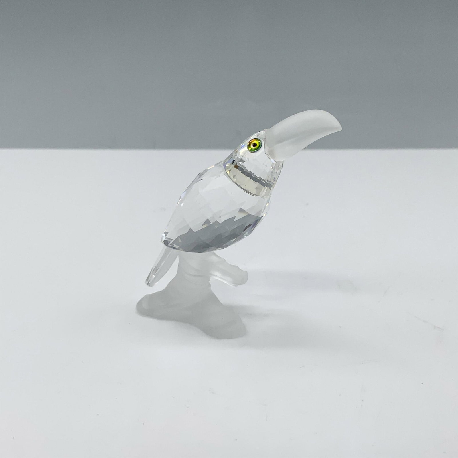 Swarovski Crystal Figurine, Toucan on a Branch: Lovely figure featuring a toucan made from clear crystal and has a frosted beak as it sits on a frosted base. This figure is part of the Up in the Trees themed group. Swarovski backstamp. This item ha