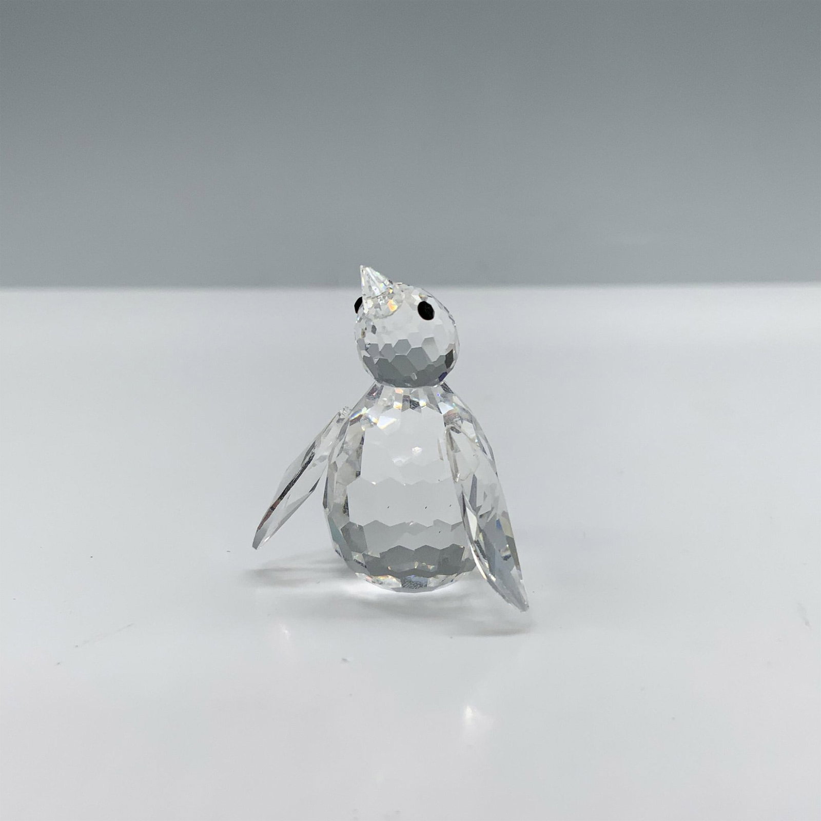 Swarovski Crystal Figurine, Mini Penguin: Splendid little figure of a penguin with a clear crystal faceted body and black eyes. This figure was part of the Kingdom of Ice and Snow collection. Swarovski backstamp. This item has its original bo