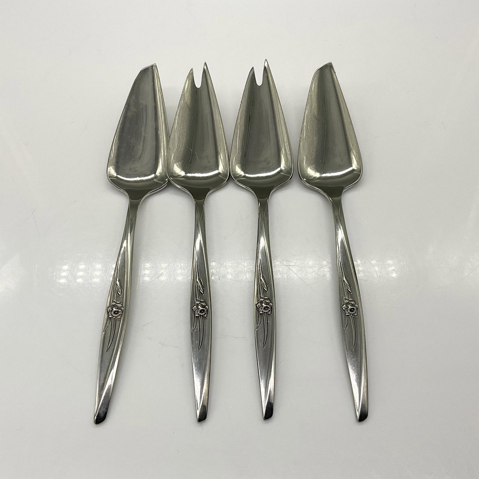 4pc 1847 Rogers Bros. Spring Charm Cheese Knife and Pick: This grouping includes a pair of solid cheese knives and a pair of solid cheese picks. Marked on the back 1847 Rogers Bros. All pieces are similar in size with the largest piece measuring 6.75"L x 1.2