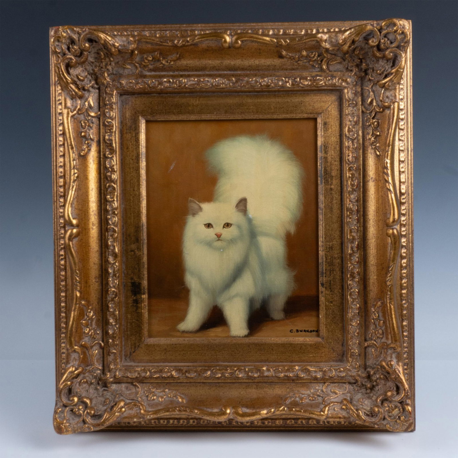 C. Swanson Persian Cat Oil on Canvass: Adorable oil painting of a Persian cat on a gilded gold floral carved frame. Frame size: 15"L x 3"W x 17.25"H. Sight size: 8"W x 10"H. Artist: C. Swanson Dimensions: See Description