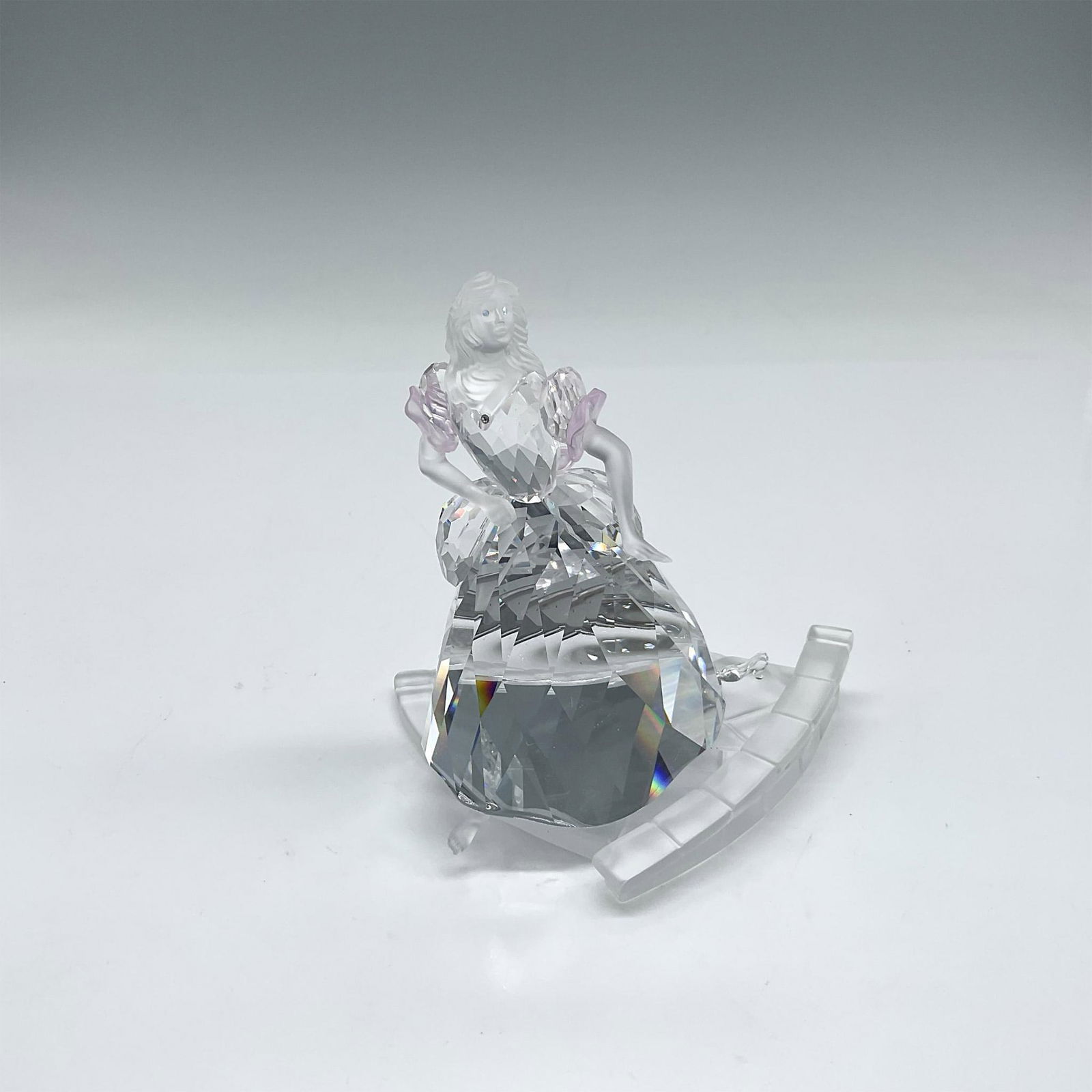 Swarovski Crystal Figurine, Cinderella: Clear crystal figure with satin crystal face and arms adorned with pink crystal accents leaving the ball when she loses her shoe. Her clear crystal slipper sits at top of stairs. Swarovski backstamp.